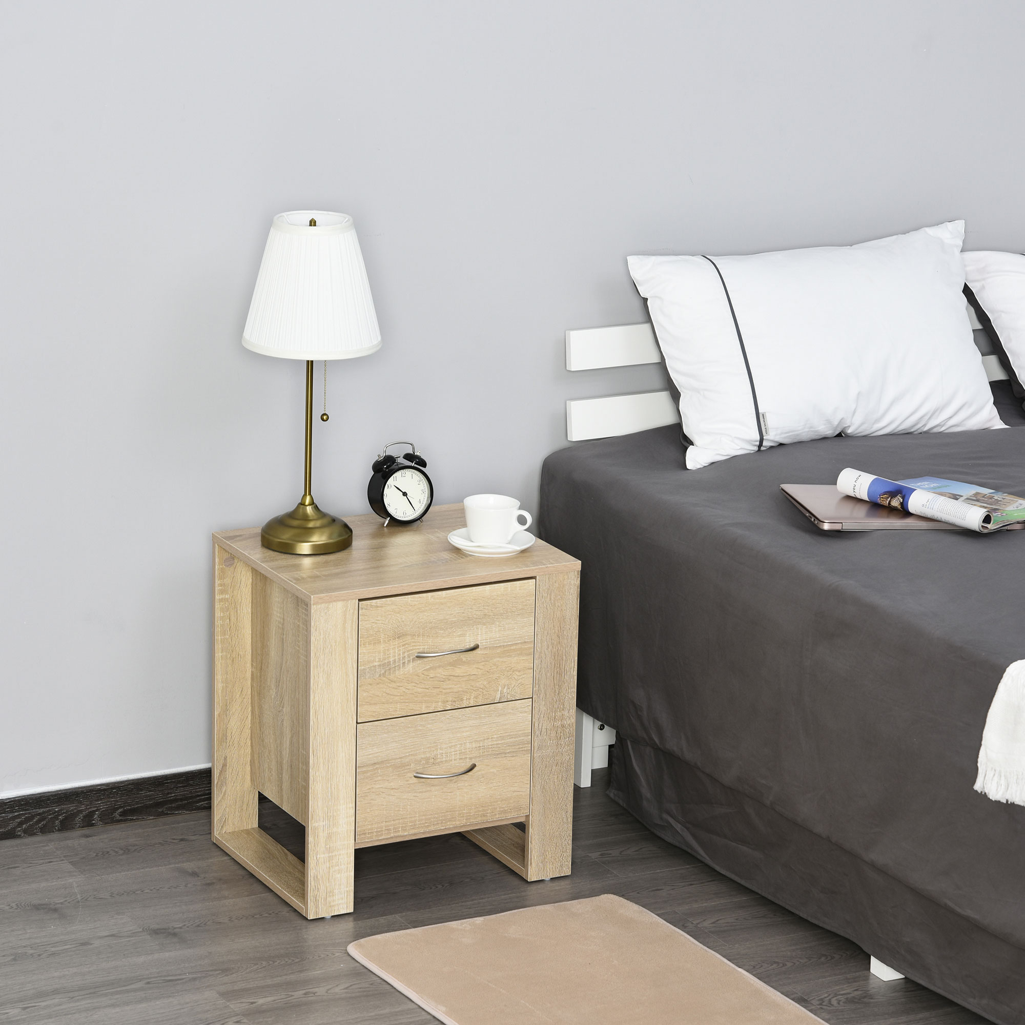 Mesita de noche de madera con lámpara, despertador, taza y cama.
