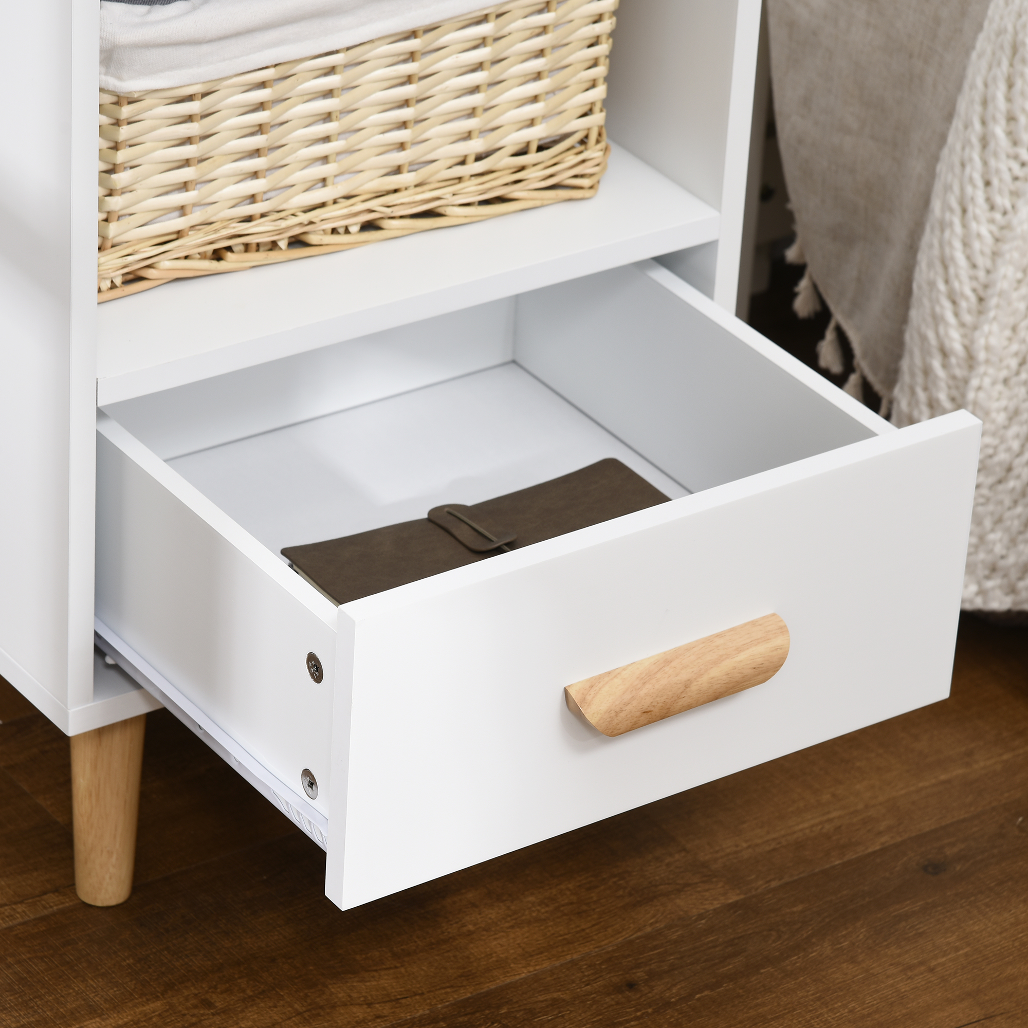 Un cajón blanco abierto con tirador de madera, contiene un cuaderno marrón.