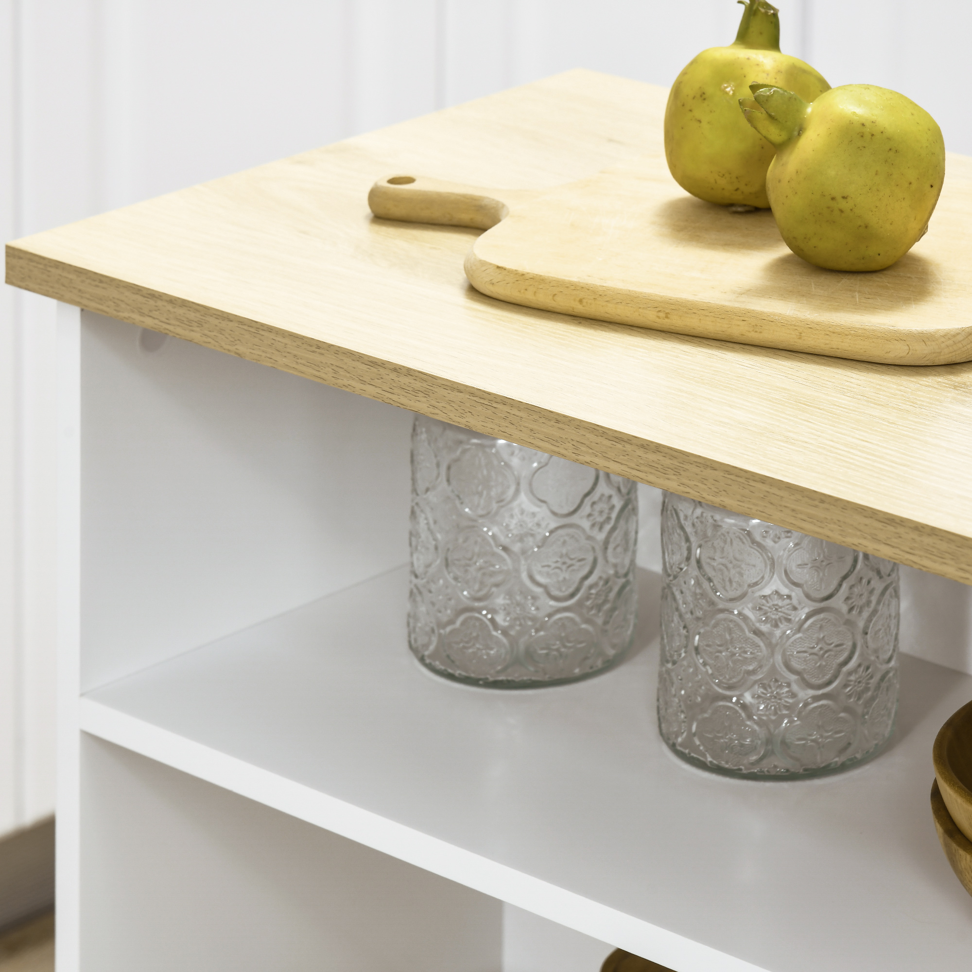 Dos frutas verdes sobre tabla de madera en estante blanco con frascos.