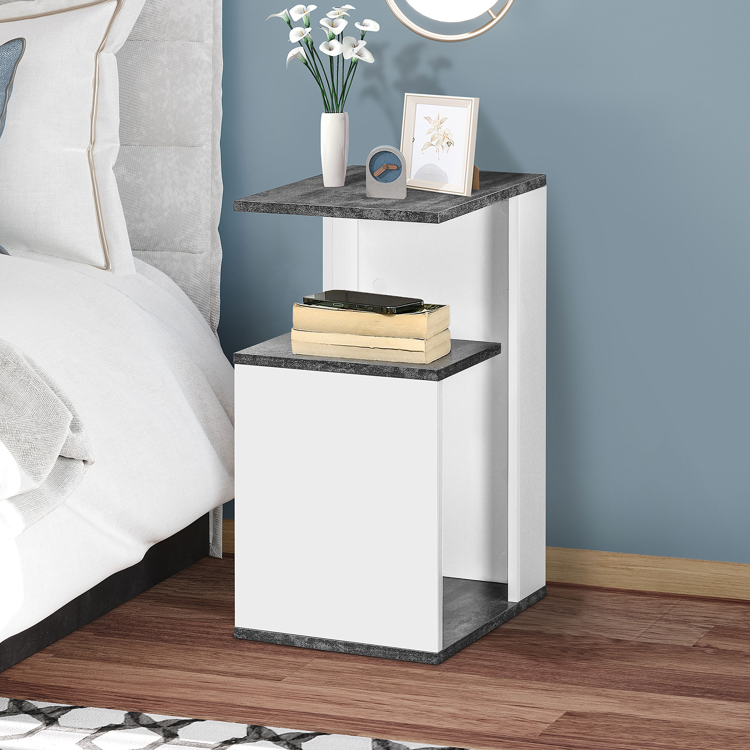 Una mesita de noche junto a una cama con ropa de cama blanca y pared azul.