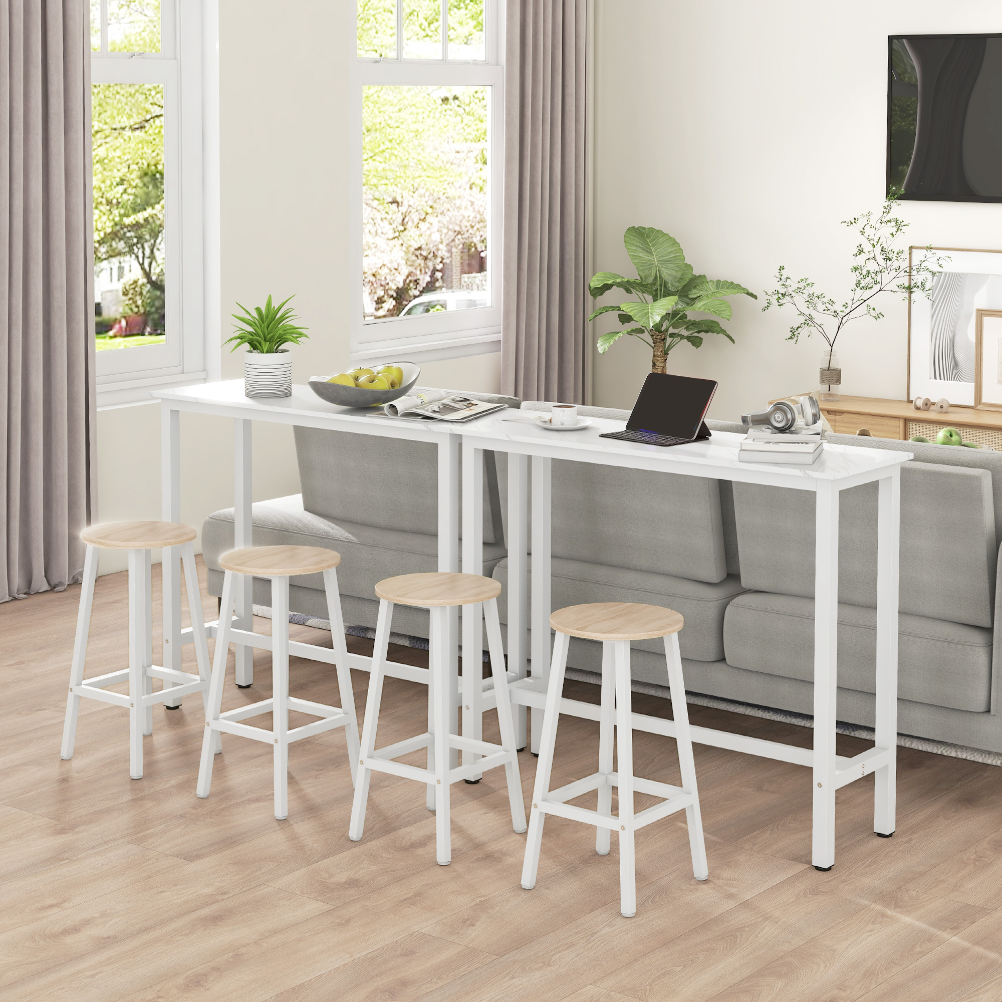Una mesa blanca larga con cuatro taburetes altos delante y un sofá al lado.