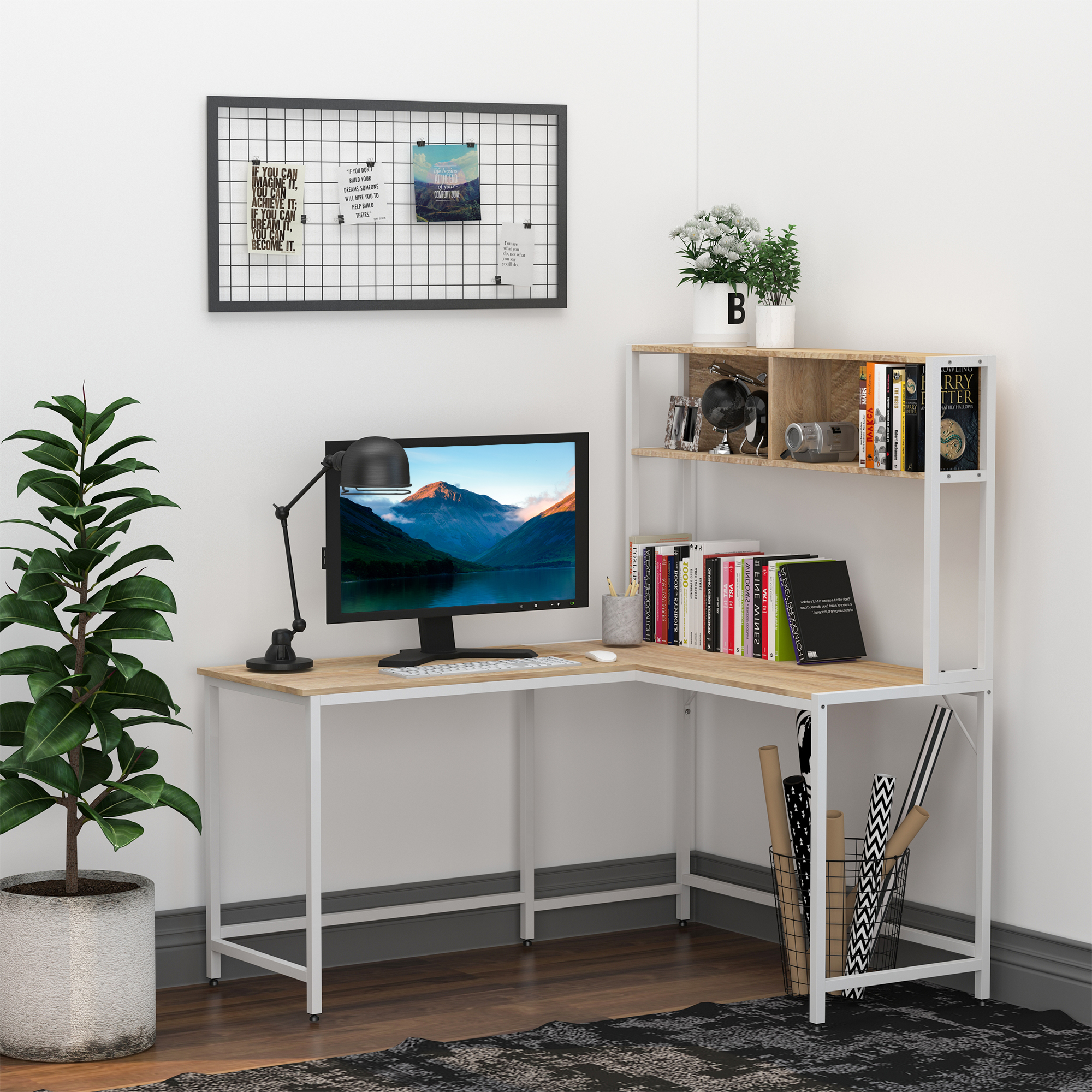 Un escritorio de esquina con monitor, lámpara, planta y libros.