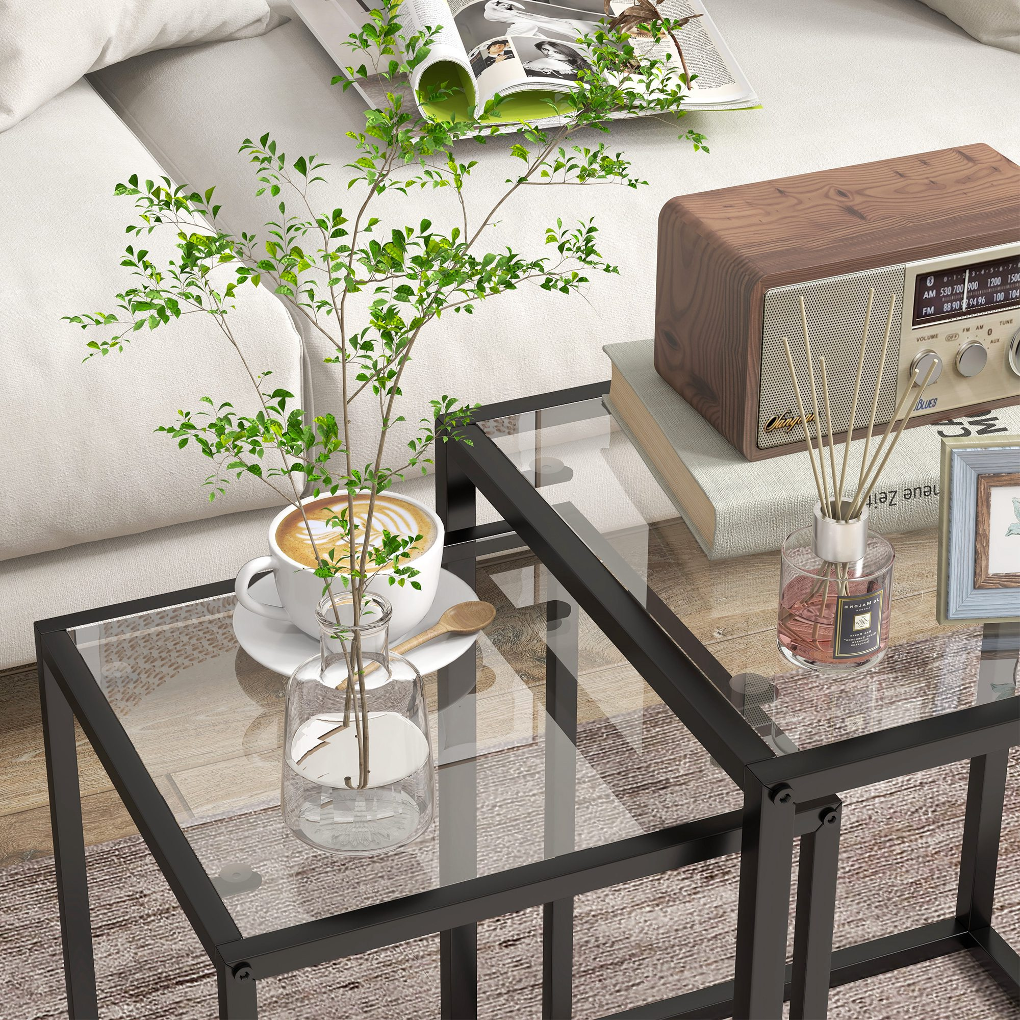 Taza de café en mesa de centro de cristal junto a radio de madera y planta.