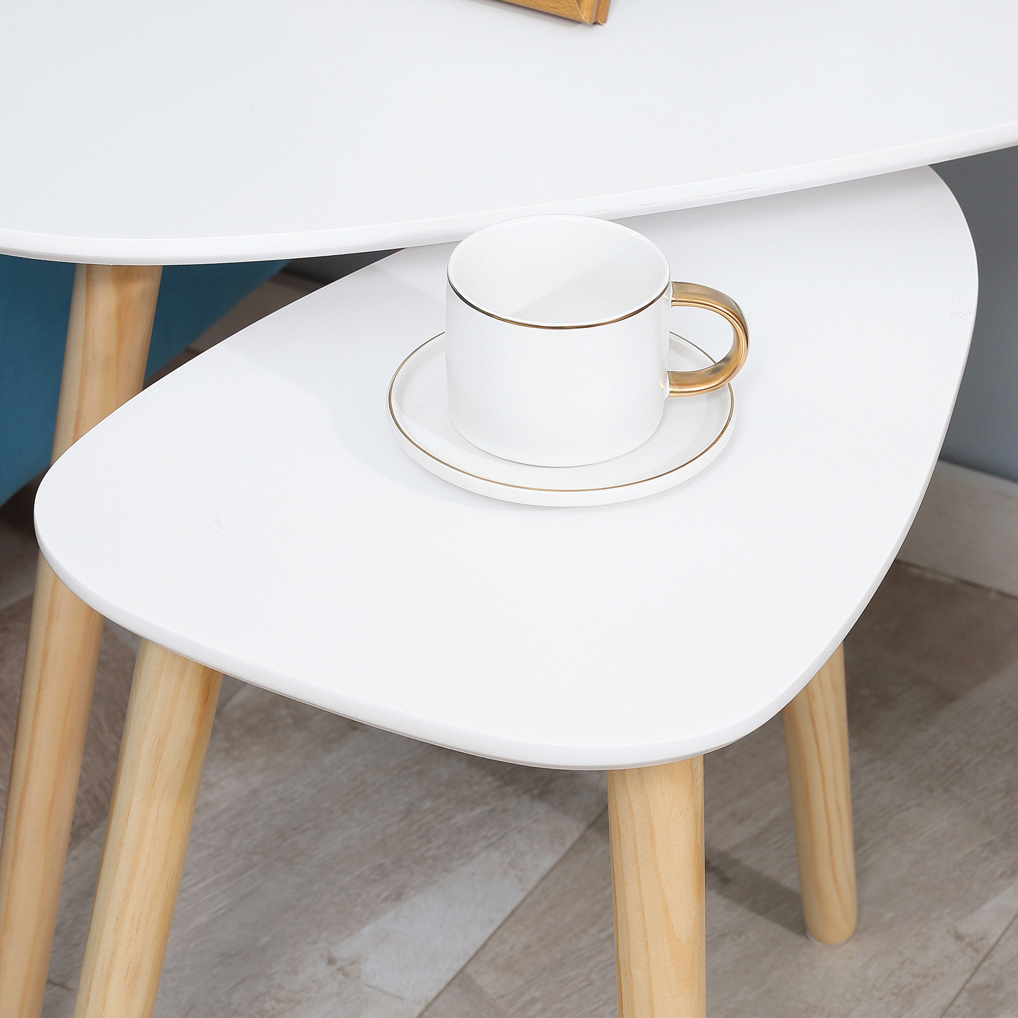 Una taza blanca con asa dorada sobre un platillo, sobre una mesa blanca.