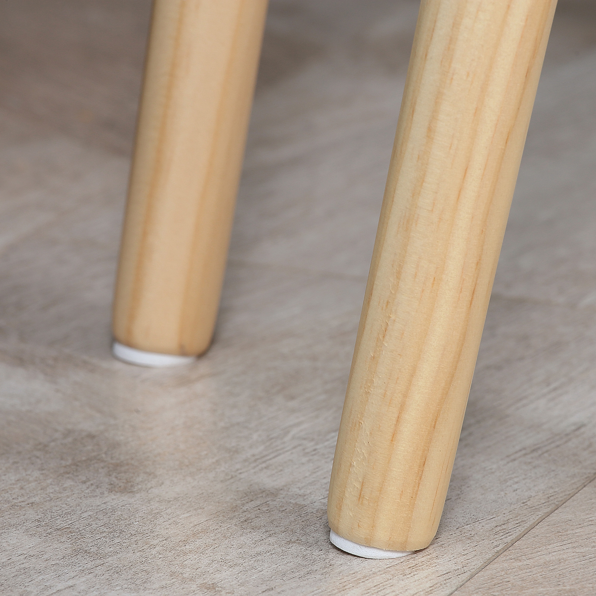 Dos patas de silla de madera con tapas blancas sobre suelo de madera.