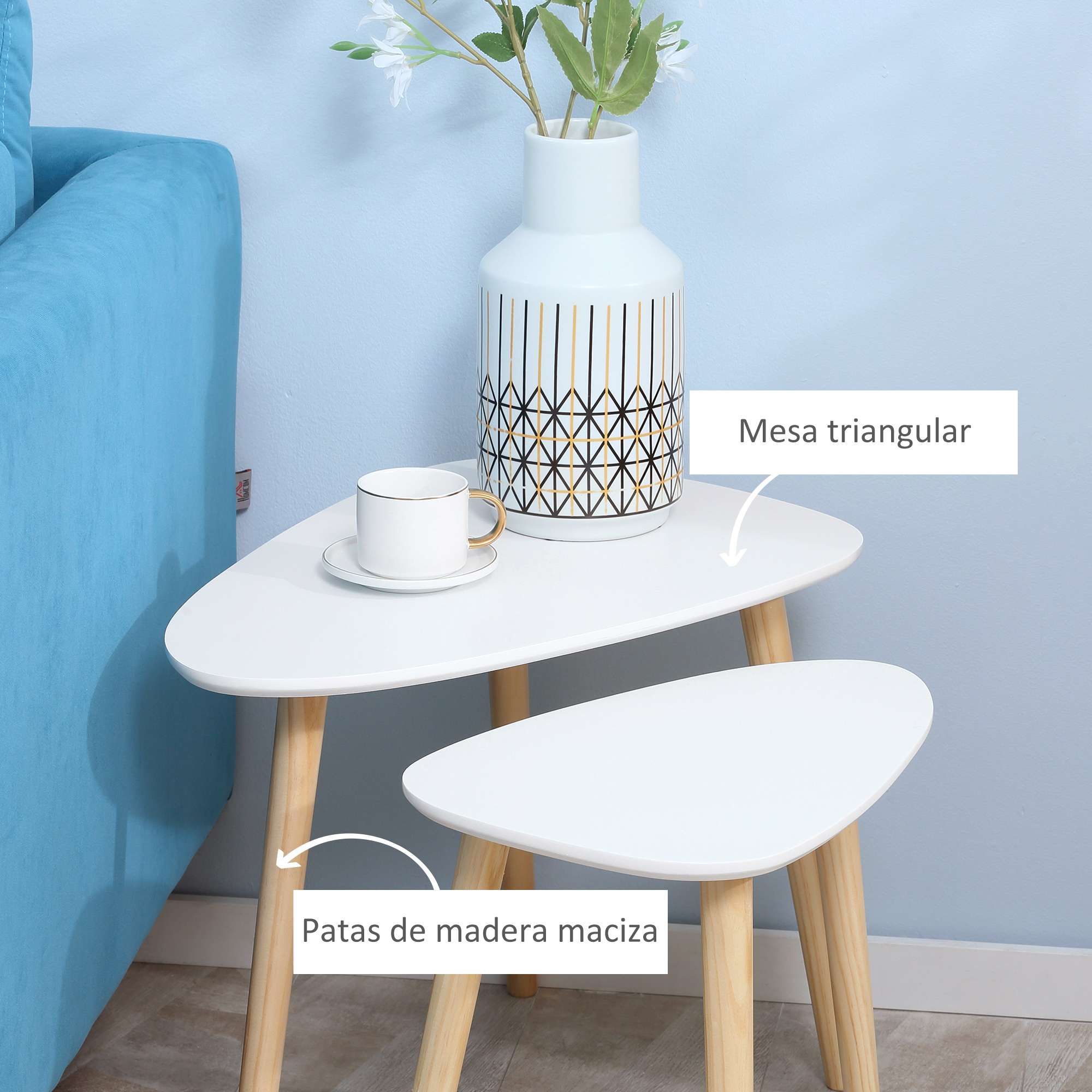 Dos mesas auxiliares triangulares blancas con patas de madera, una mesa tiene una taza.