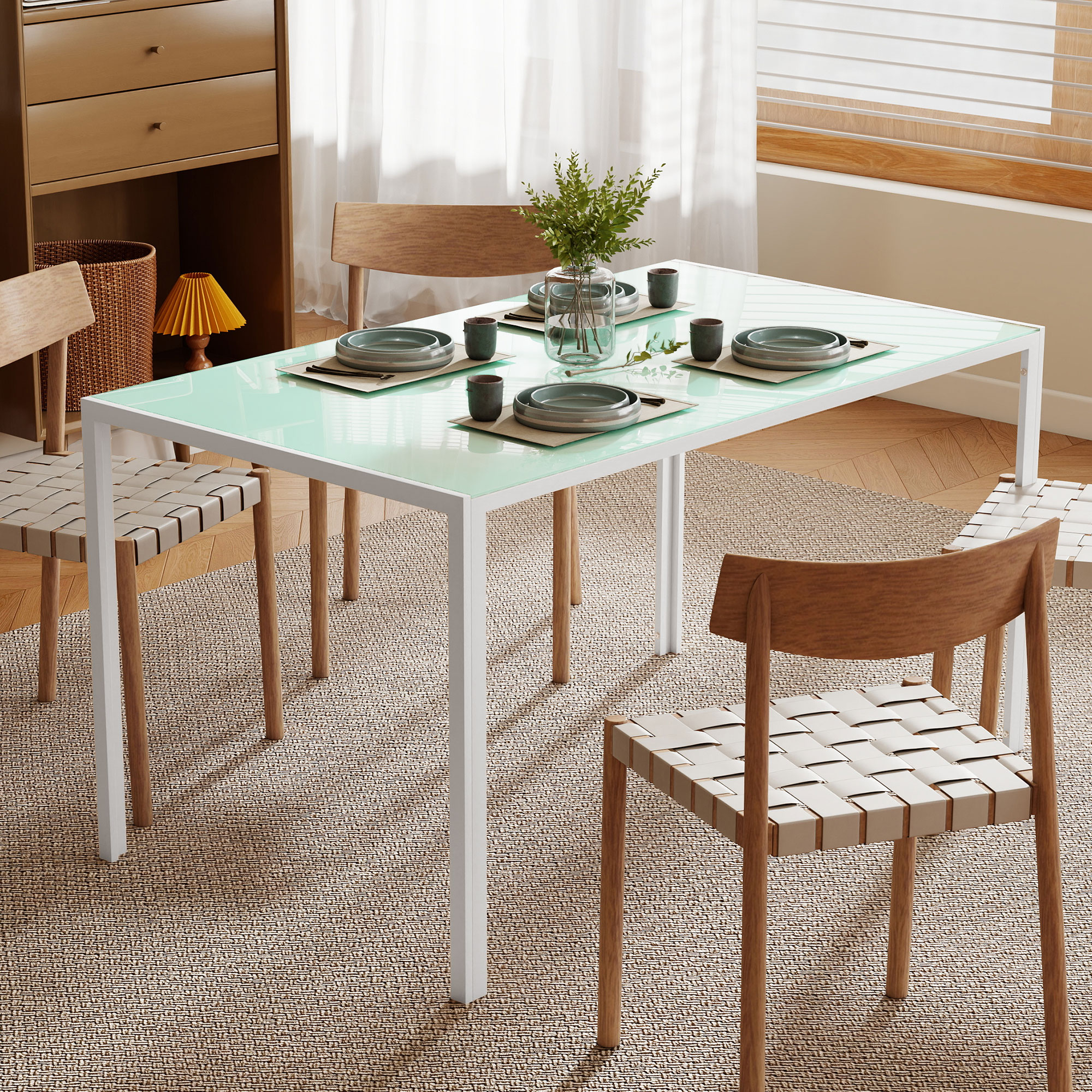 Una mesa de comedor con tapa de cristal turquesa, cuatro servicios y un jarrón con plantas.