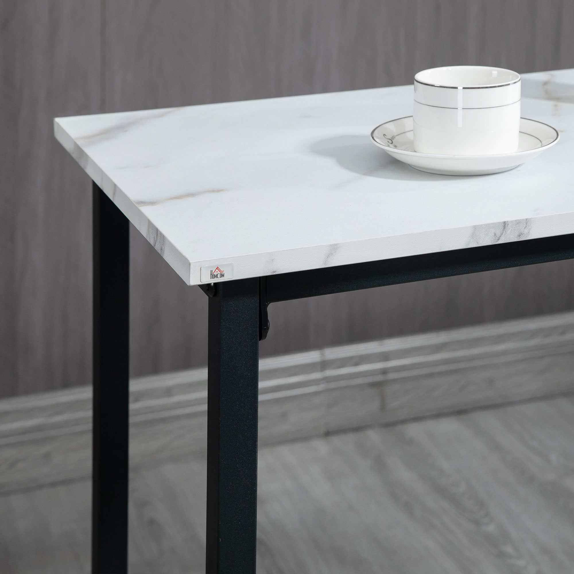 Una taza y platillo blancos sobre una mesa de mármol con patas negras.