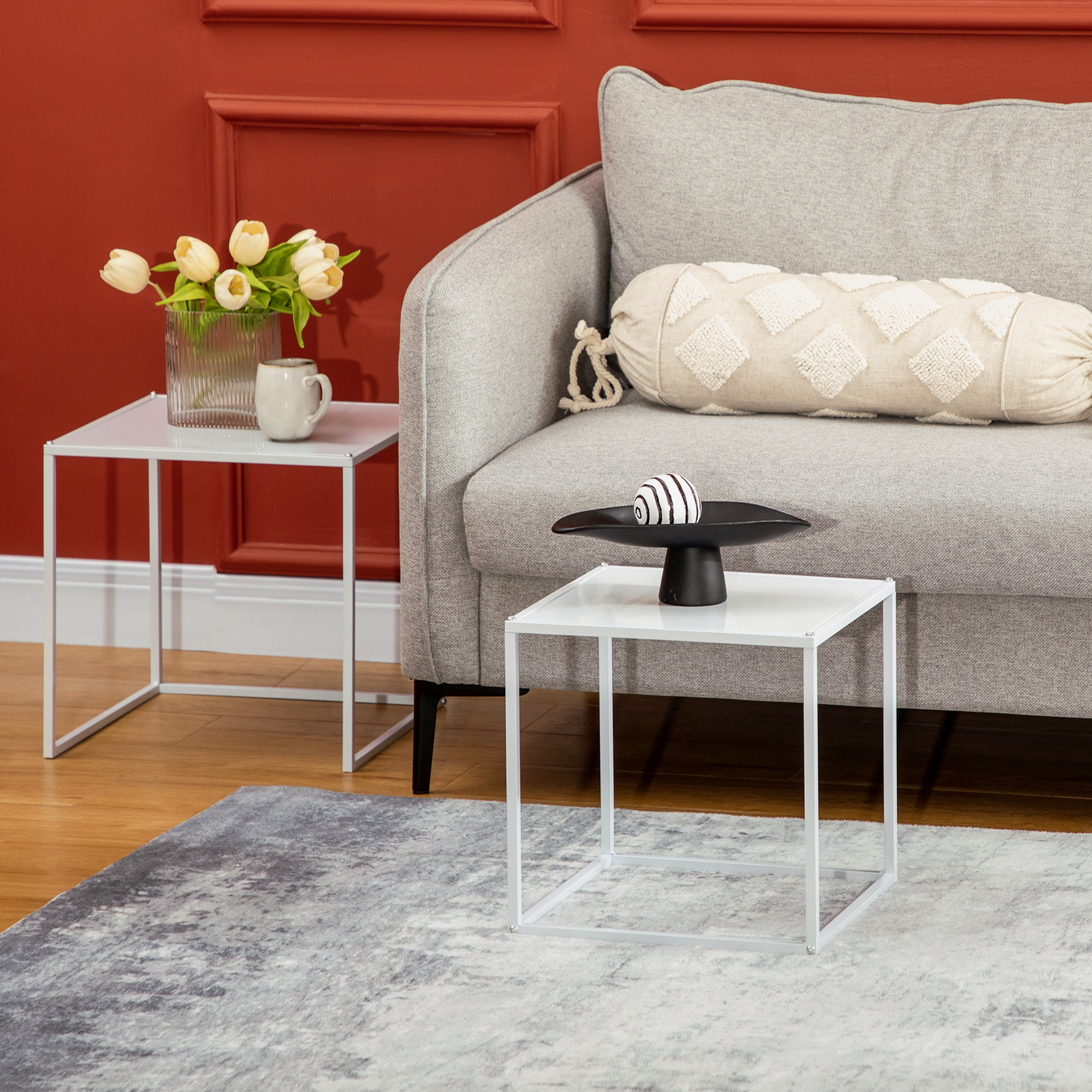 Un sofá gris con cojines junto a una mesa auxiliar con decoración.