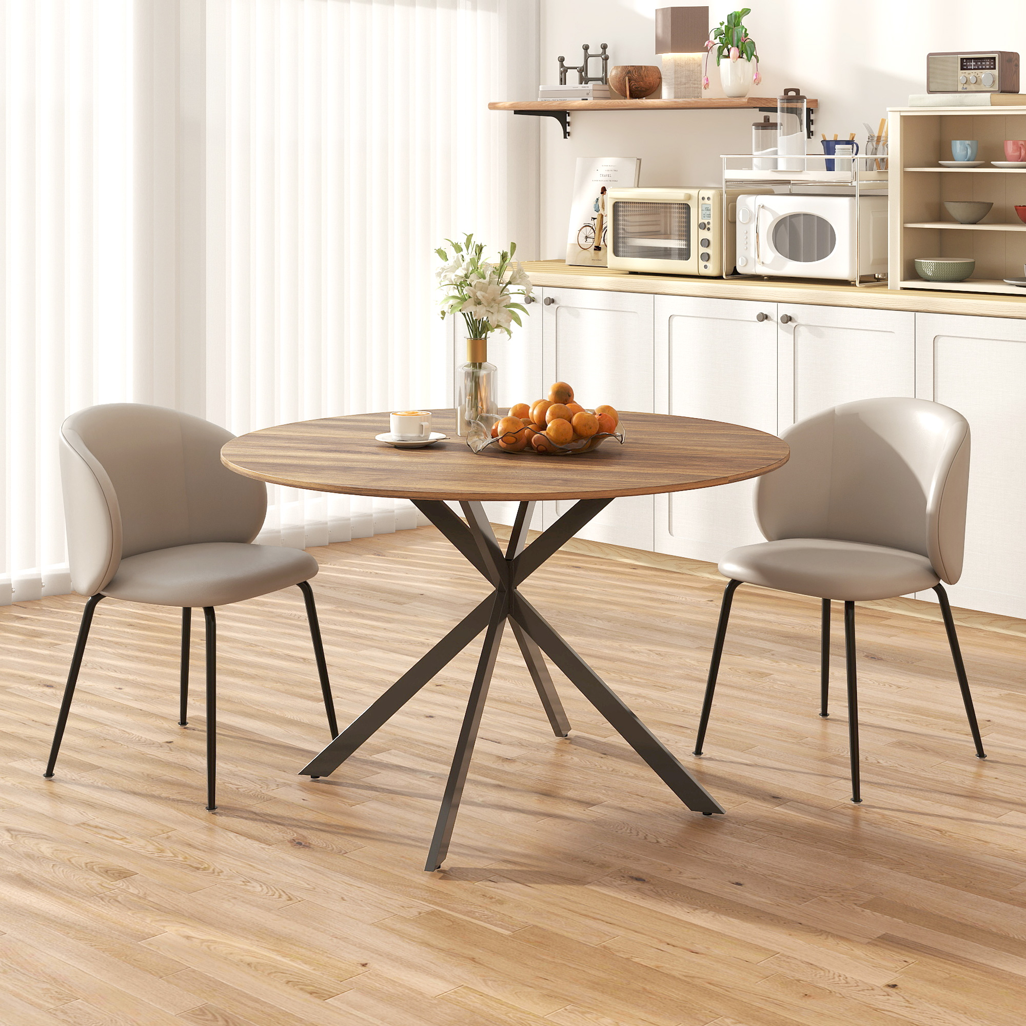 Una mesa redonda de madera con dos sillas en una cocina. Hay naranjas en un cuenco sobre la mesa.