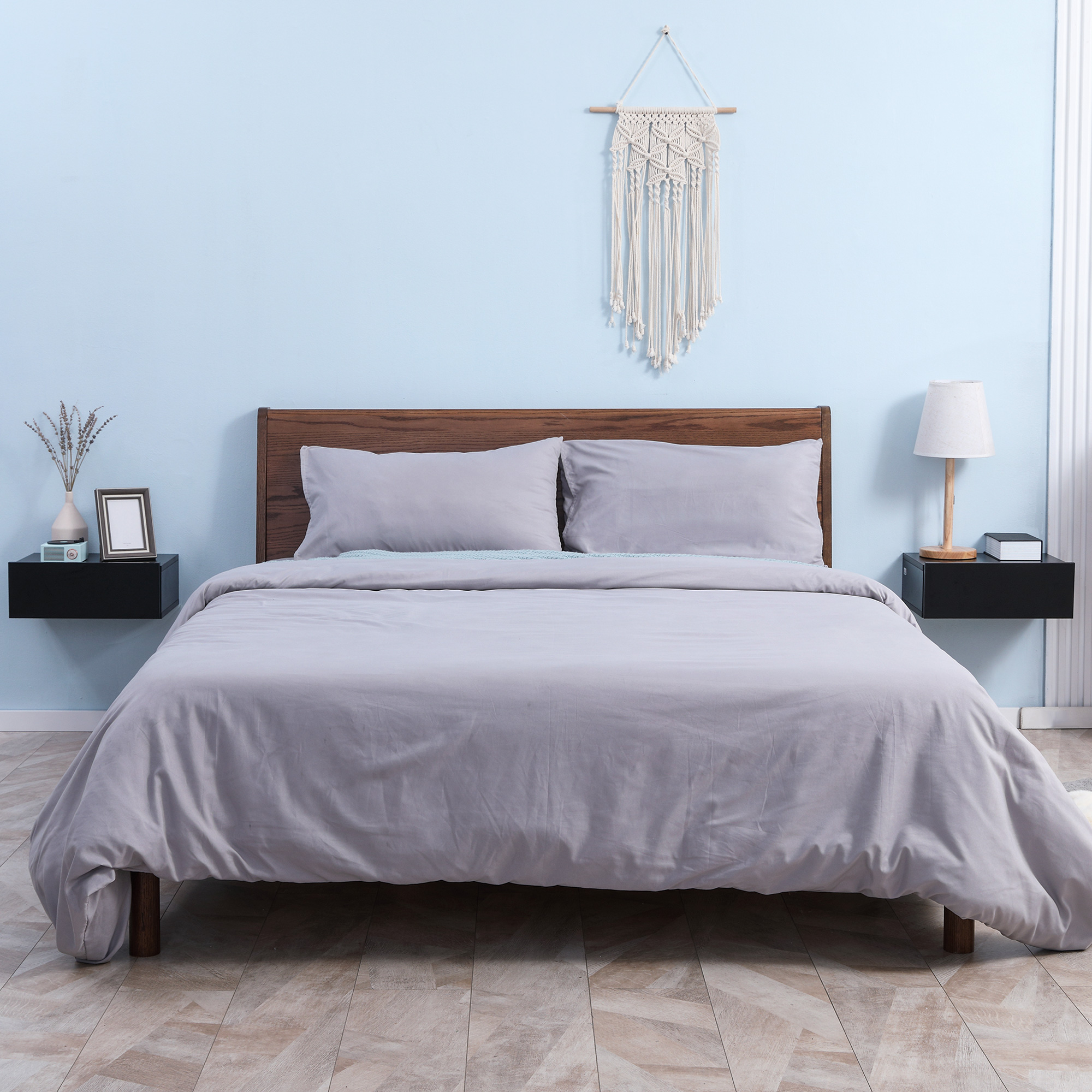 Un dormitorio azul claro con una cama doble y ropa de cama gris.