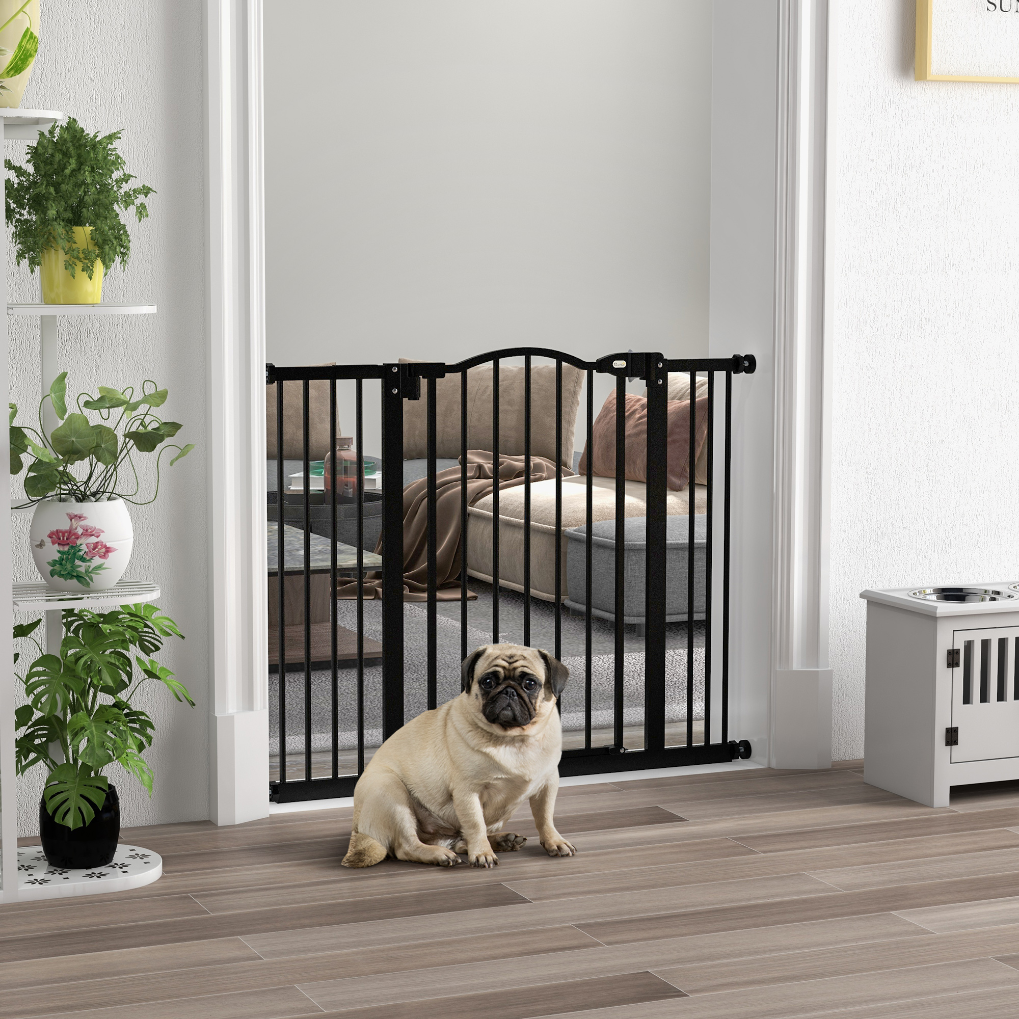 Un pug se sienta ante una barrera de bebé negra, con una sala de estar detrás.