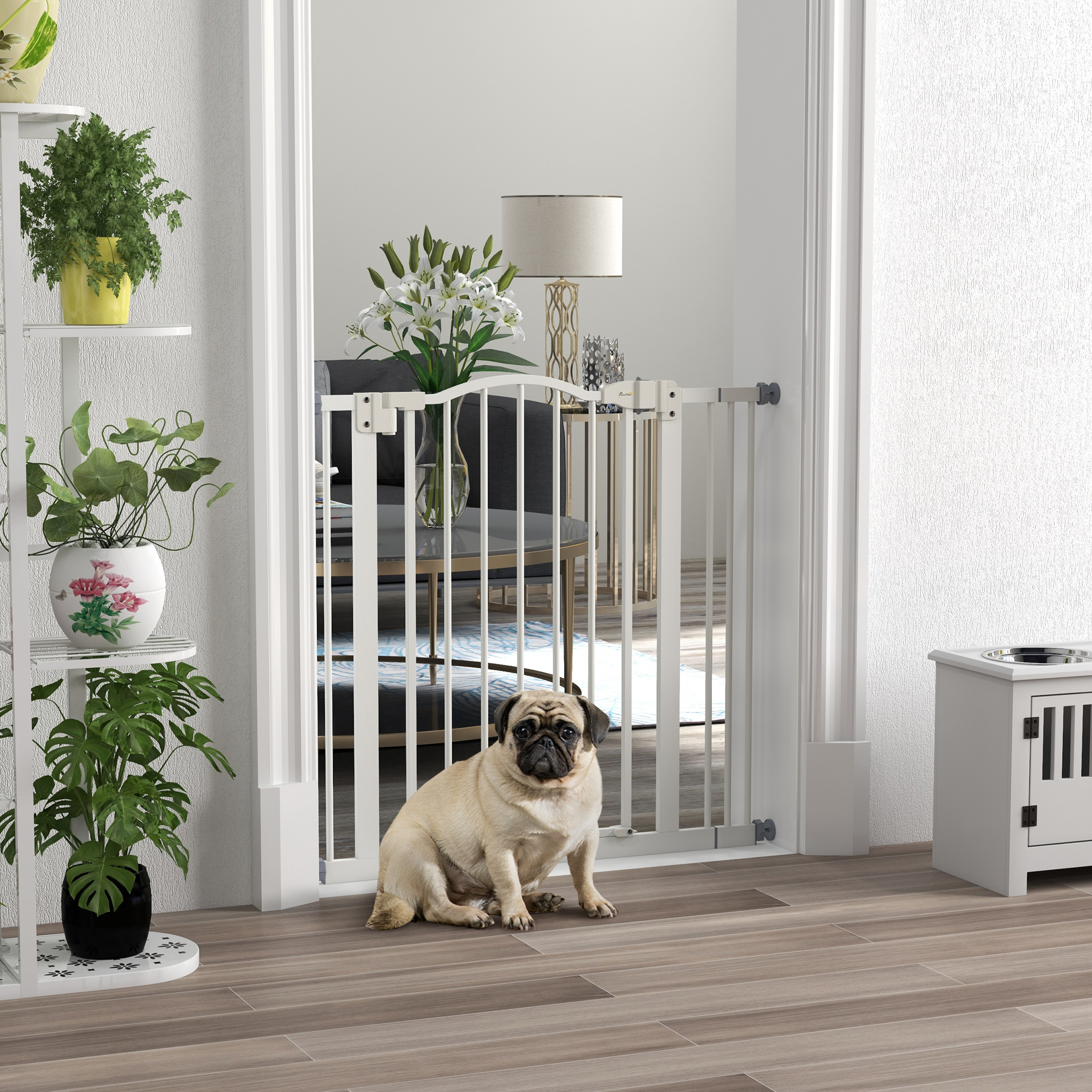 Un pug se sienta frente a una barrera de bebé blanca en el interior.