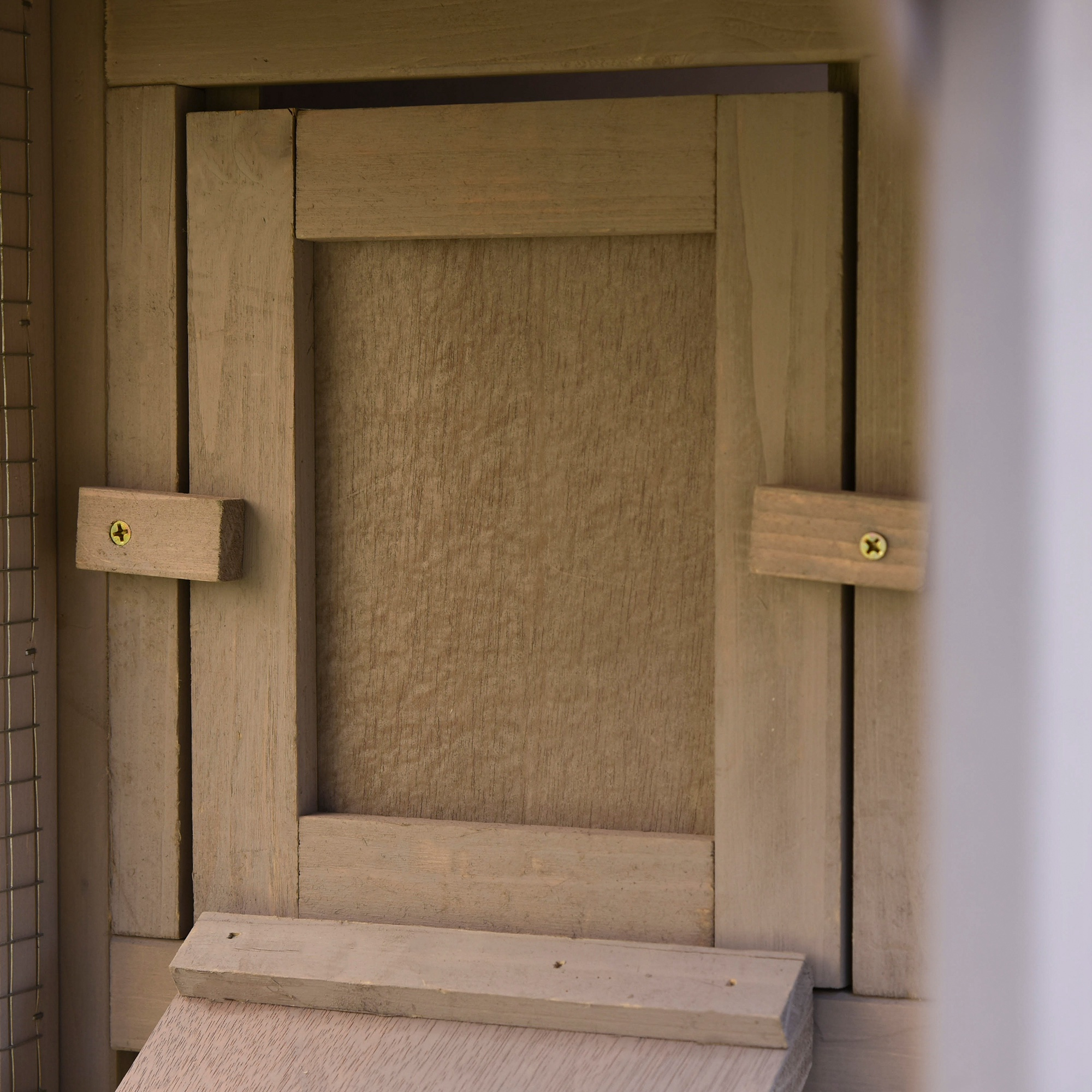 Puerta de madera de pajarera con pestillos y malla de alambre.