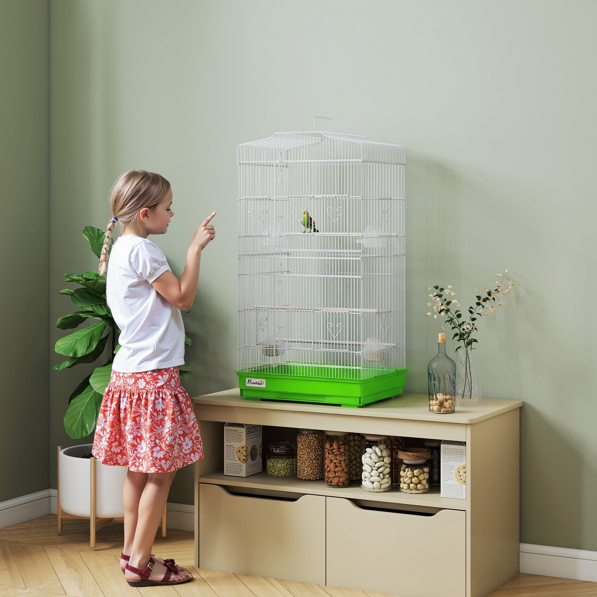 Una niña señala a un pájaro en una jaula sobre tarros llenos de frutos secos.