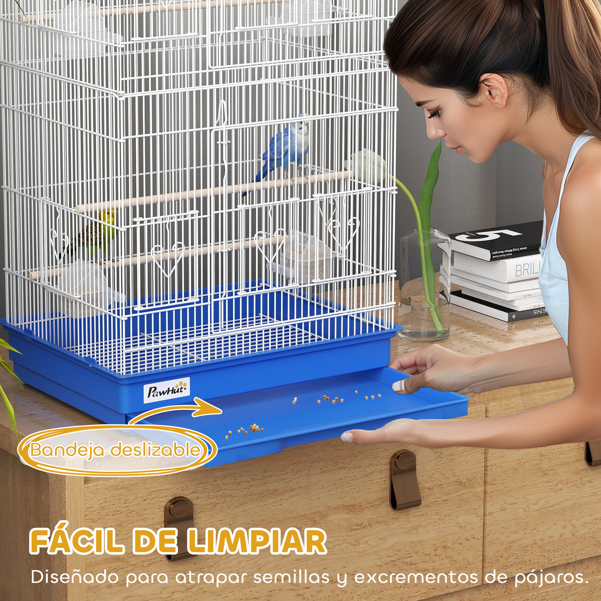 Una mujer limpia un cajón de jaula de pájaros con semillas y excrementos.