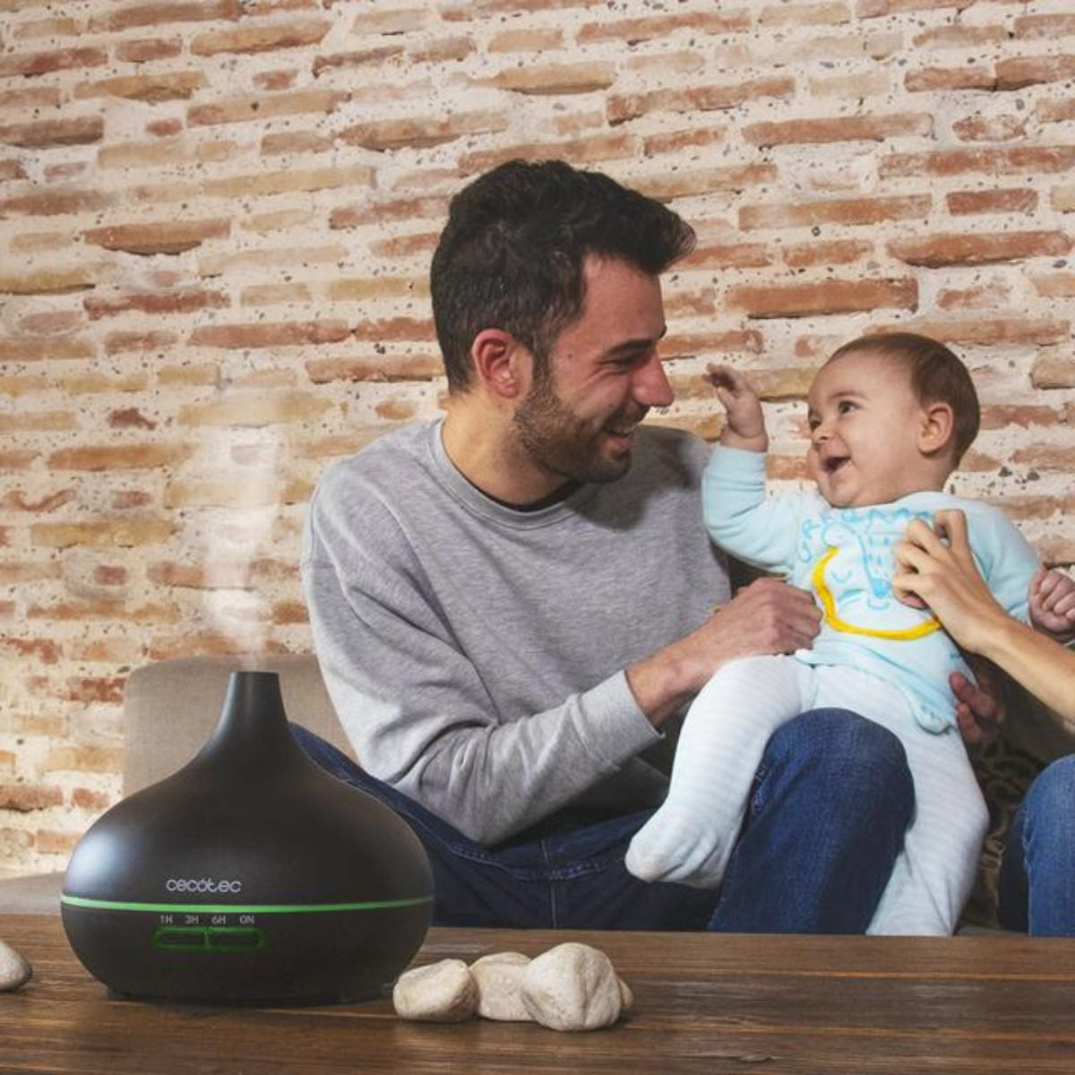 Mężczyzna trzyma dziecko; dyfuzor wydziela dym.