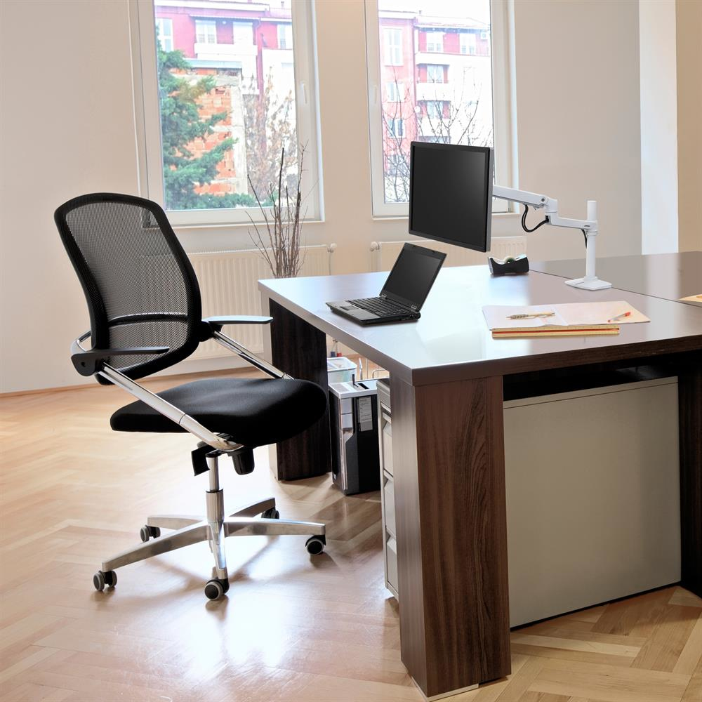 Scena ufficio con scrivania, sedia, laptop e monitor. Luce naturale entra.