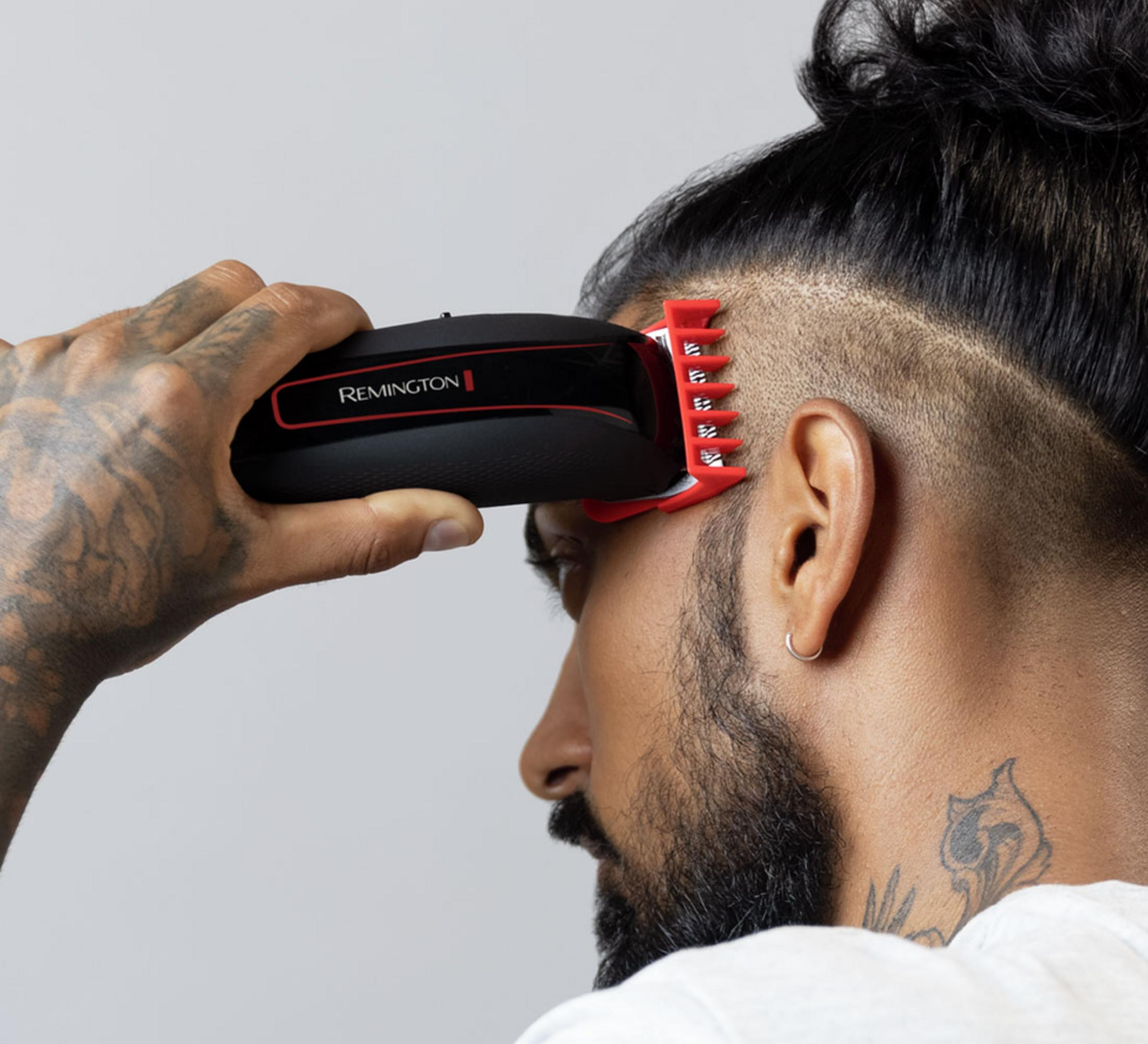 Un uomo si taglia la testa con un tagliacapelli Remington con pettine rosso.