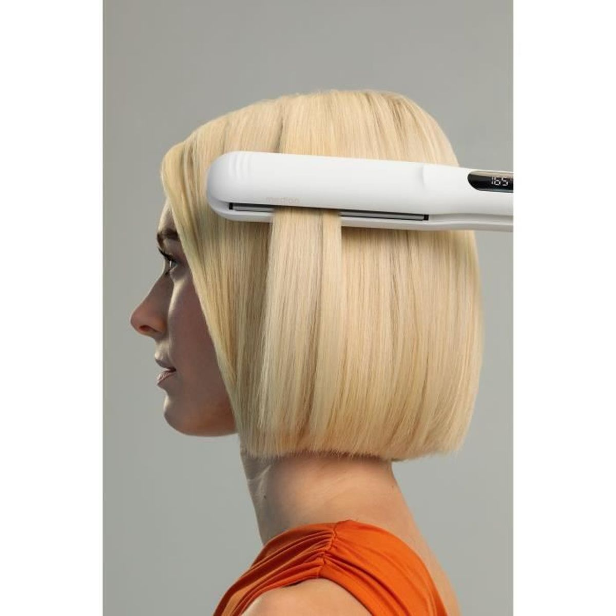 Kobieta z blond bobem prostuje włosy białą prostownicą.