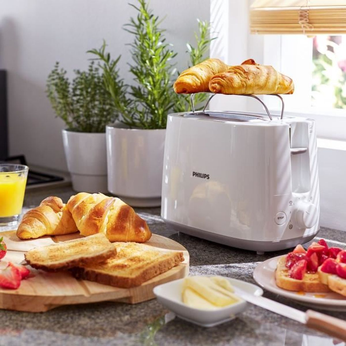 Biały toster z croissantami i tostami na blacie kuchennym.