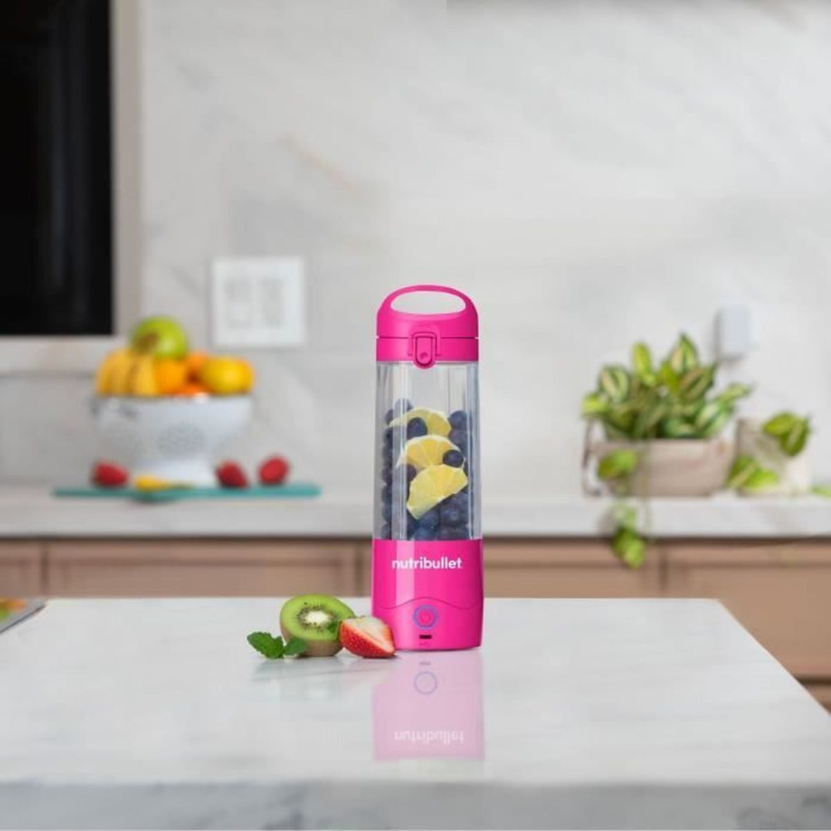 Różowy blender Nutribullet wypełniony borówkami i plasterkami cytryny.