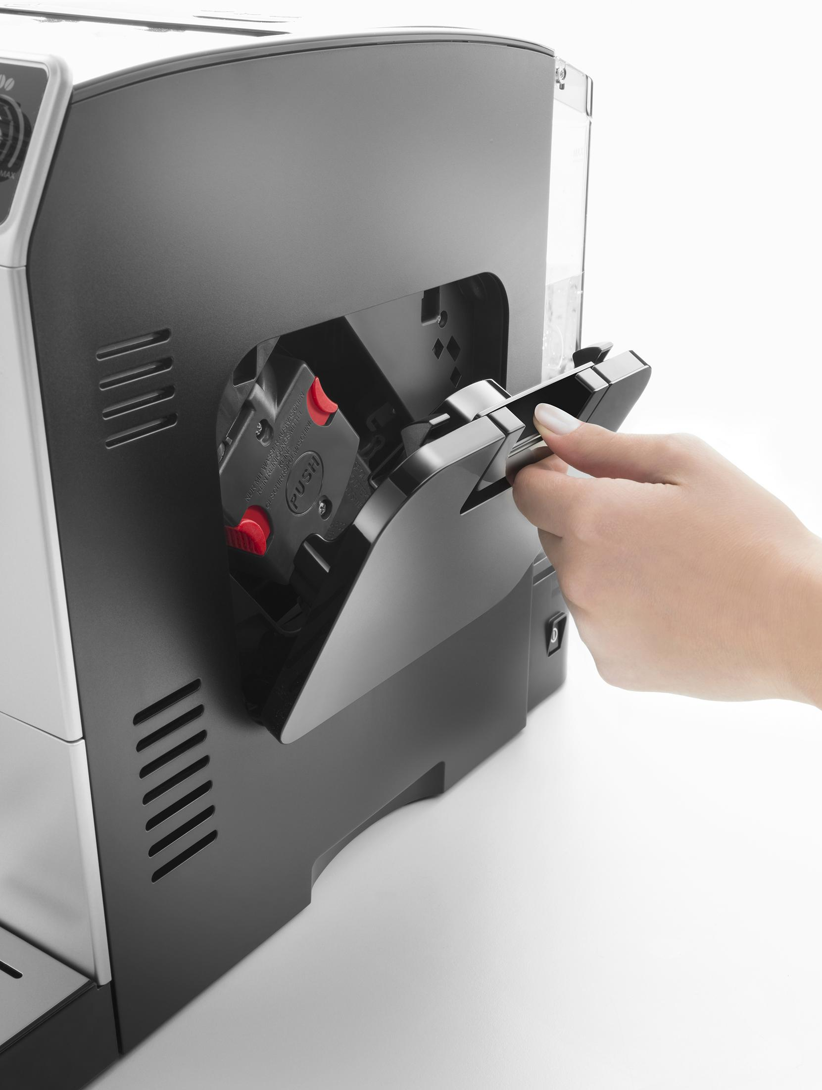 Ręka otwiera klapkę ekspresu do kawy, odsłaniając szufladę.
