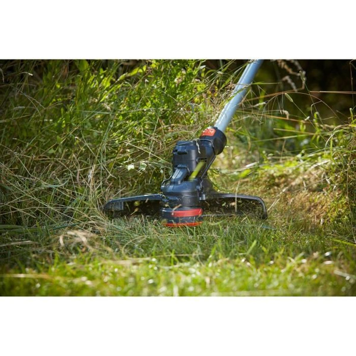 Un cortabordes corta hierba verde densa y maleza alta cerca.