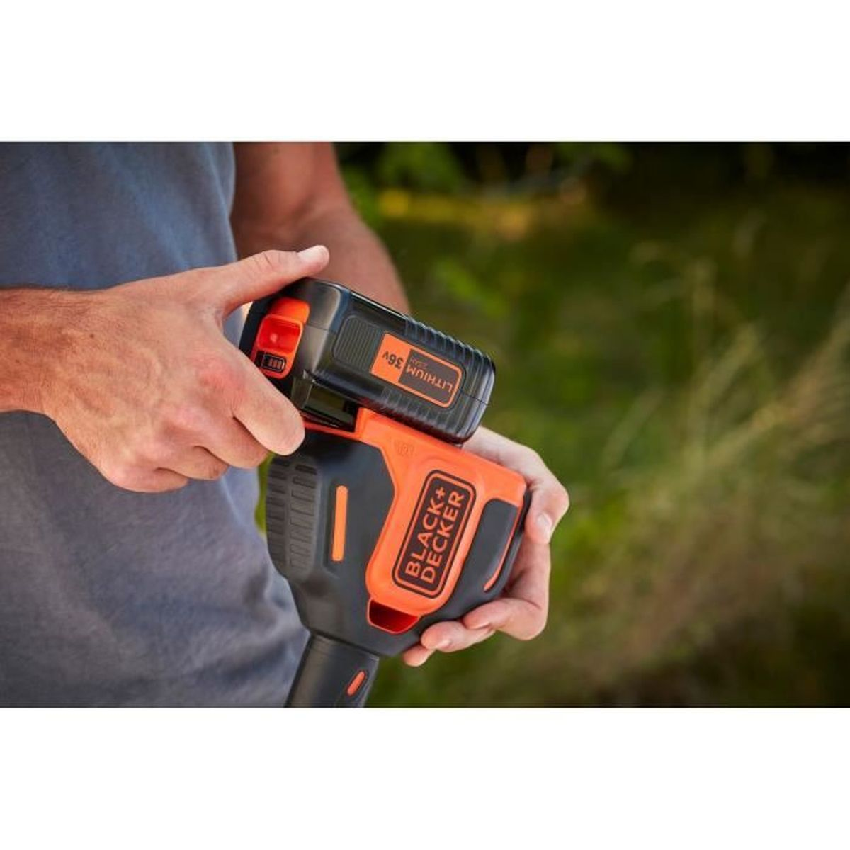 Hombre sujetando un cortasetos Black+Decker negro y naranja con batería de 36V.