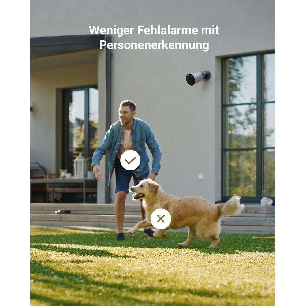 Mężczyzna bawi się z psem na trawniku przed domem. Zamontowana jest kamera.