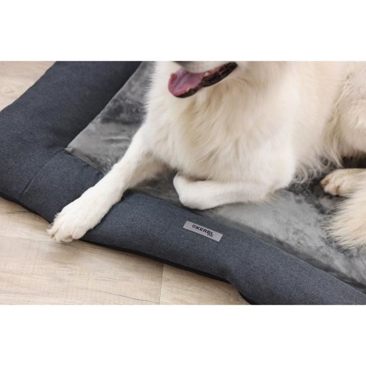 A white dog rests on a grey dog bed with a marble pattern.