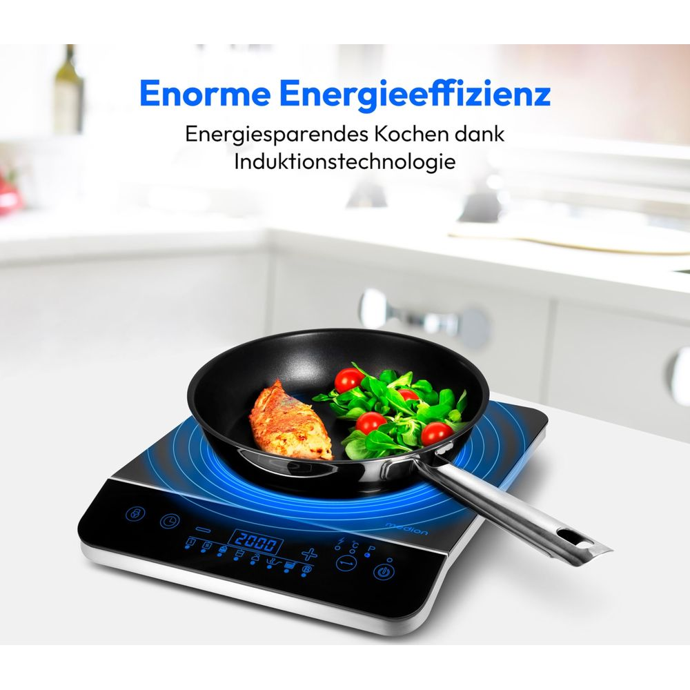 Płyta indukcyjna z patelnią, rybą i sałatką. Niebieskie podświetlenie.