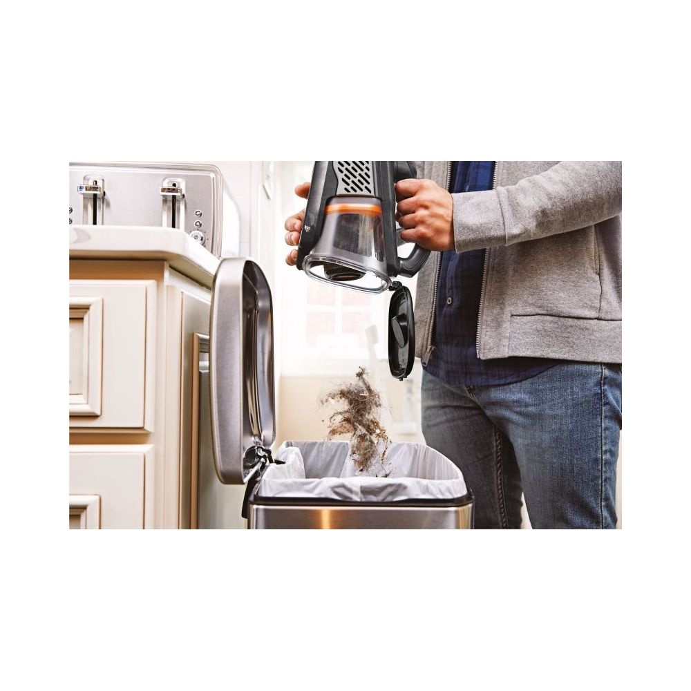 Osoba opróżnia odkurzacz ręczny do kuchennego kosza na śmieci.