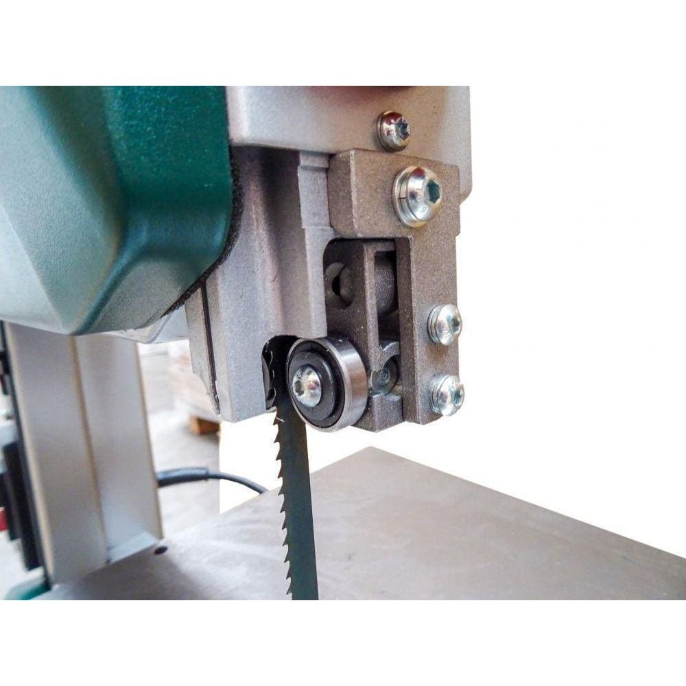 Close-up of a band saw blade with a guide roller and metal housing.