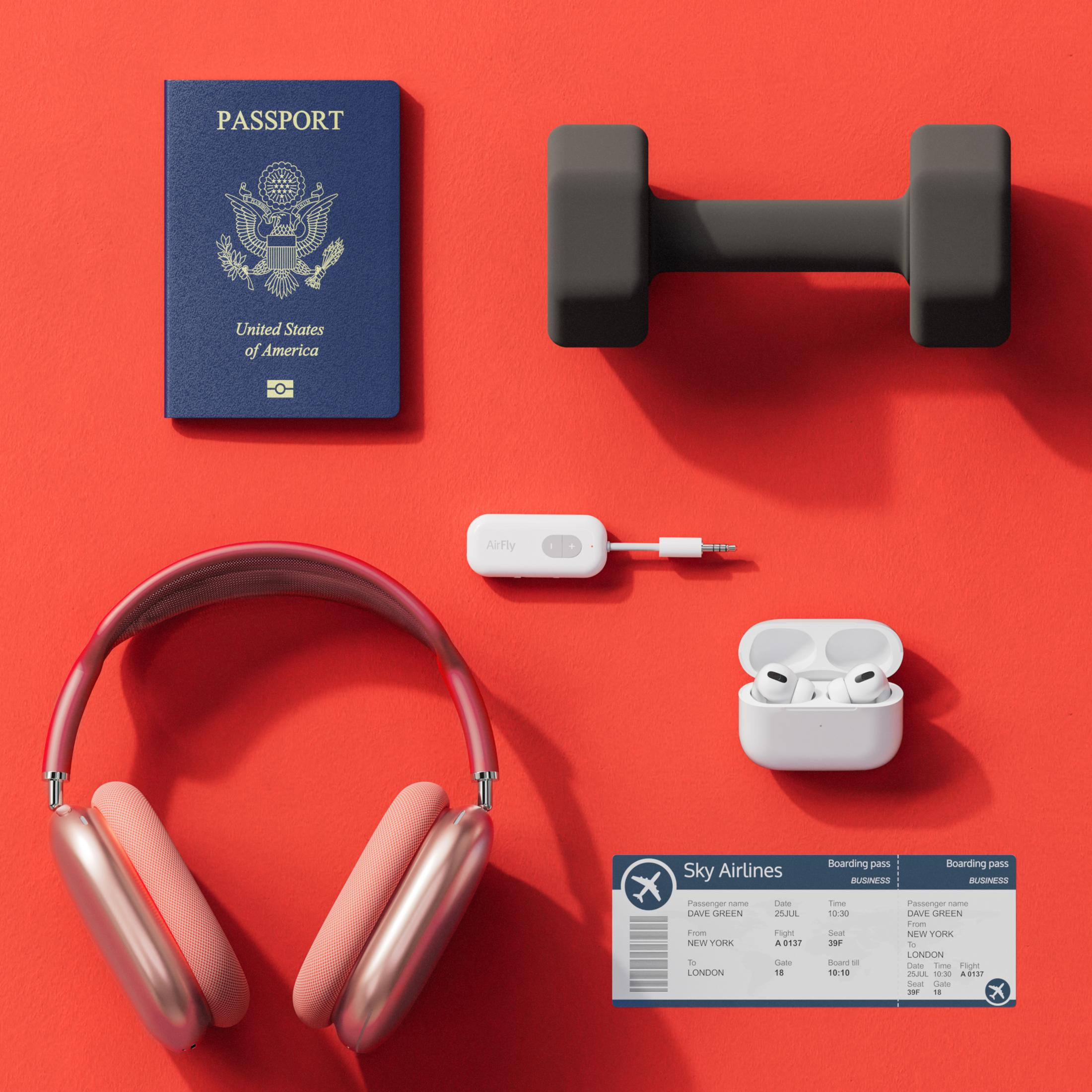 Ein US-Pass, Kopfhörer, ein Dumbbell, ein Airfly-Adapter und Ohrhörer auf rotem Grund.