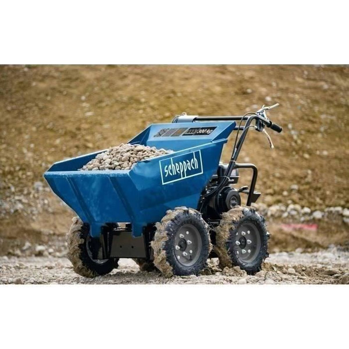 Una carriola a motore blu Scheppach piena di pietre si trova su un terreno fangoso.