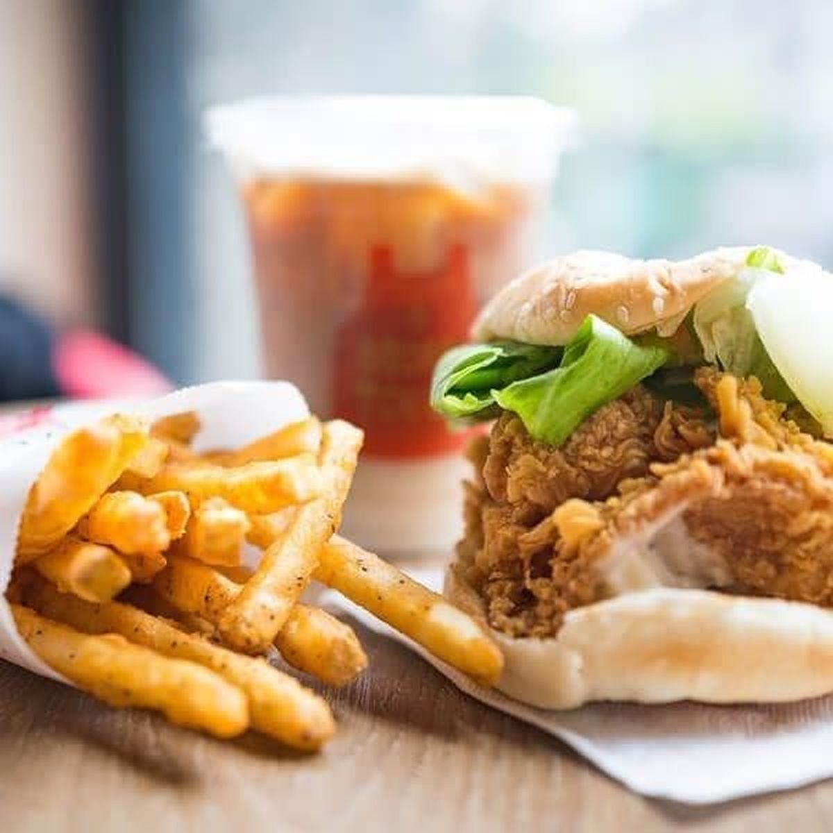 Chrupiąca kanapka z kurczakiem, sałatą, frytkami i napojem.