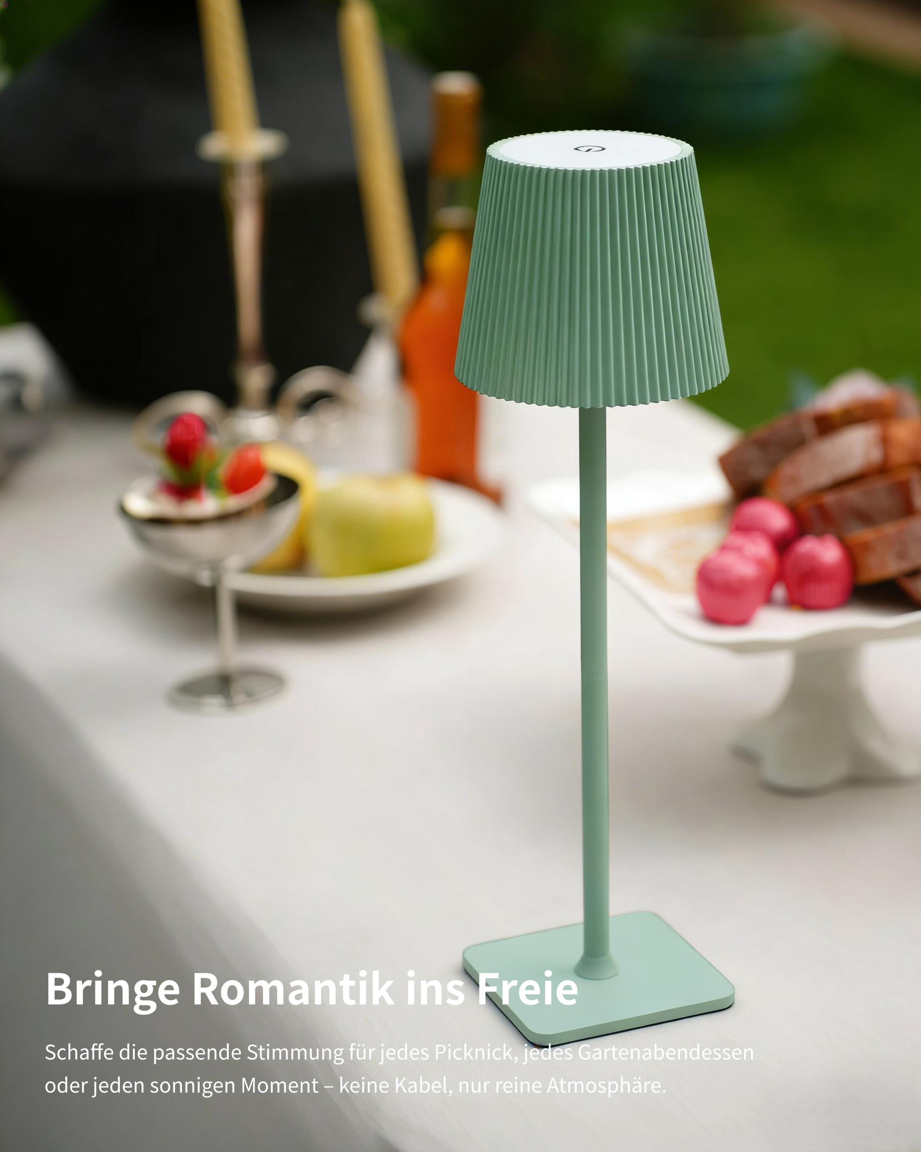 Grüne Lampe auf Tisch mit Essen und Kerzen im Garten.