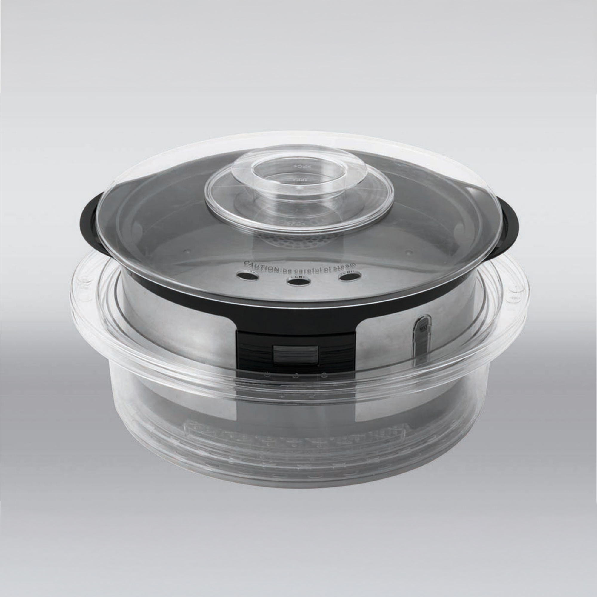 A silver steamer with a clear lid sits on a gray background.