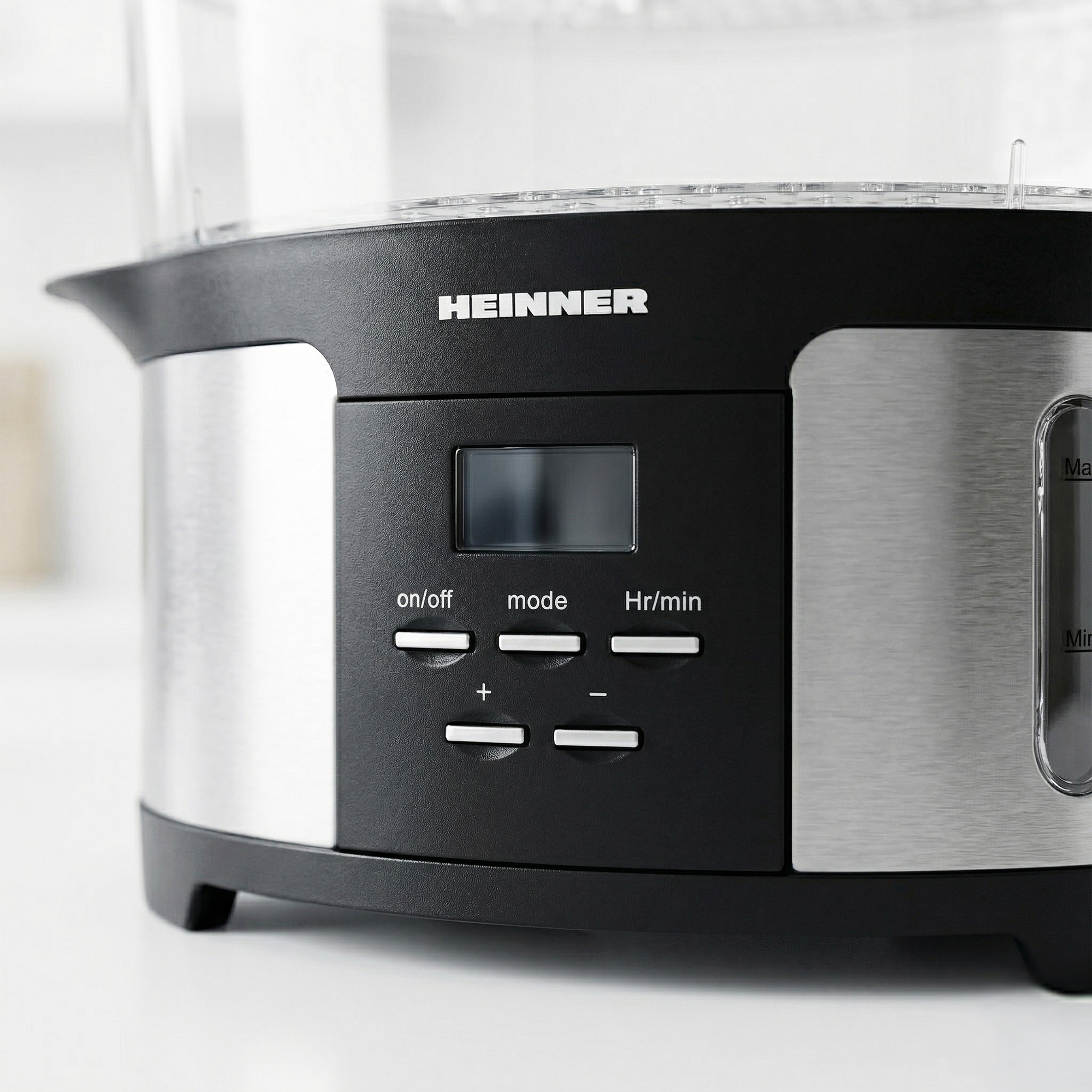 Close-up of a black HEINNER food steamer with silver accents and control buttons.