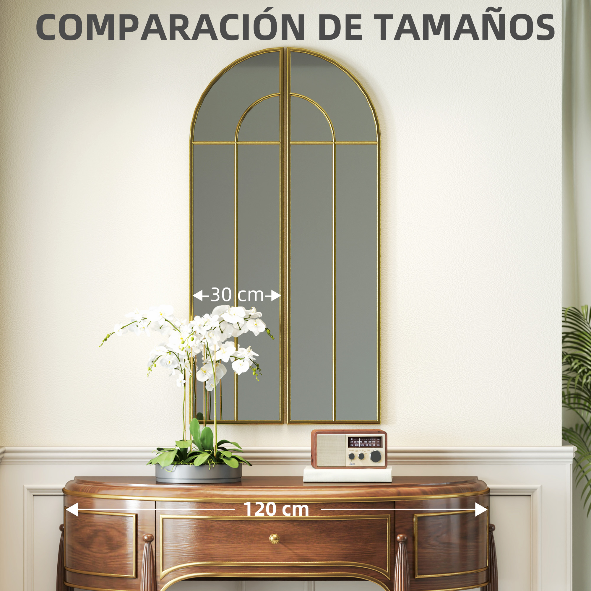 Un espejo arqueado con marco dorado cuelga sobre una consola de madera con flores y radio.