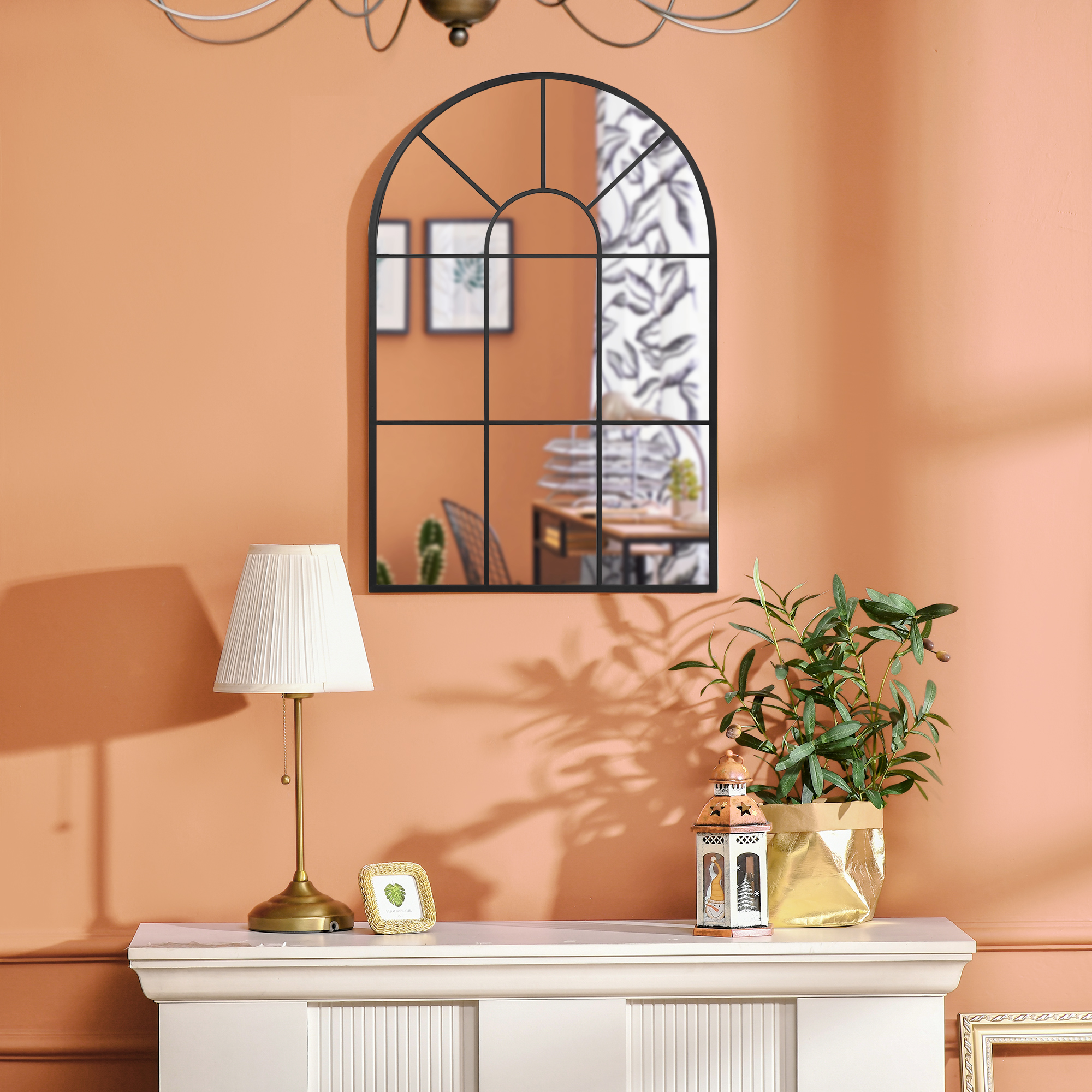 Una repisa moderna con decoración: lámpara, marco de fotos, planta y farol contra pared melocotón.