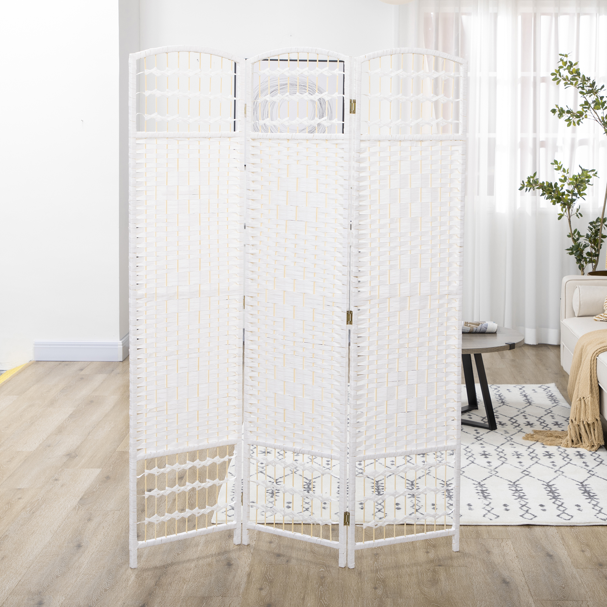 Un divisor de ambientes blanco de tres paneles está sobre un suelo de madera junto a una alfombra.