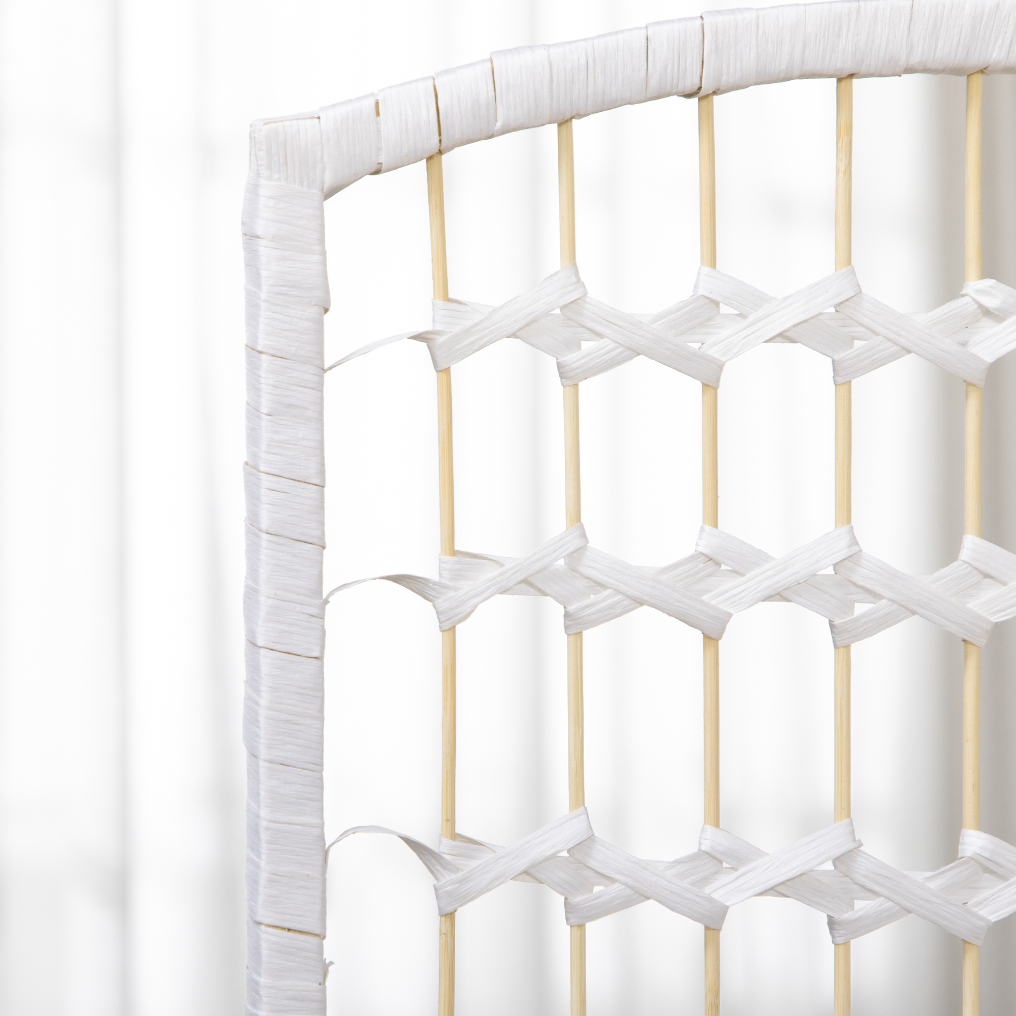 Primer plano de mueble blanco tejido con varillas de madera y mimbre blanco.