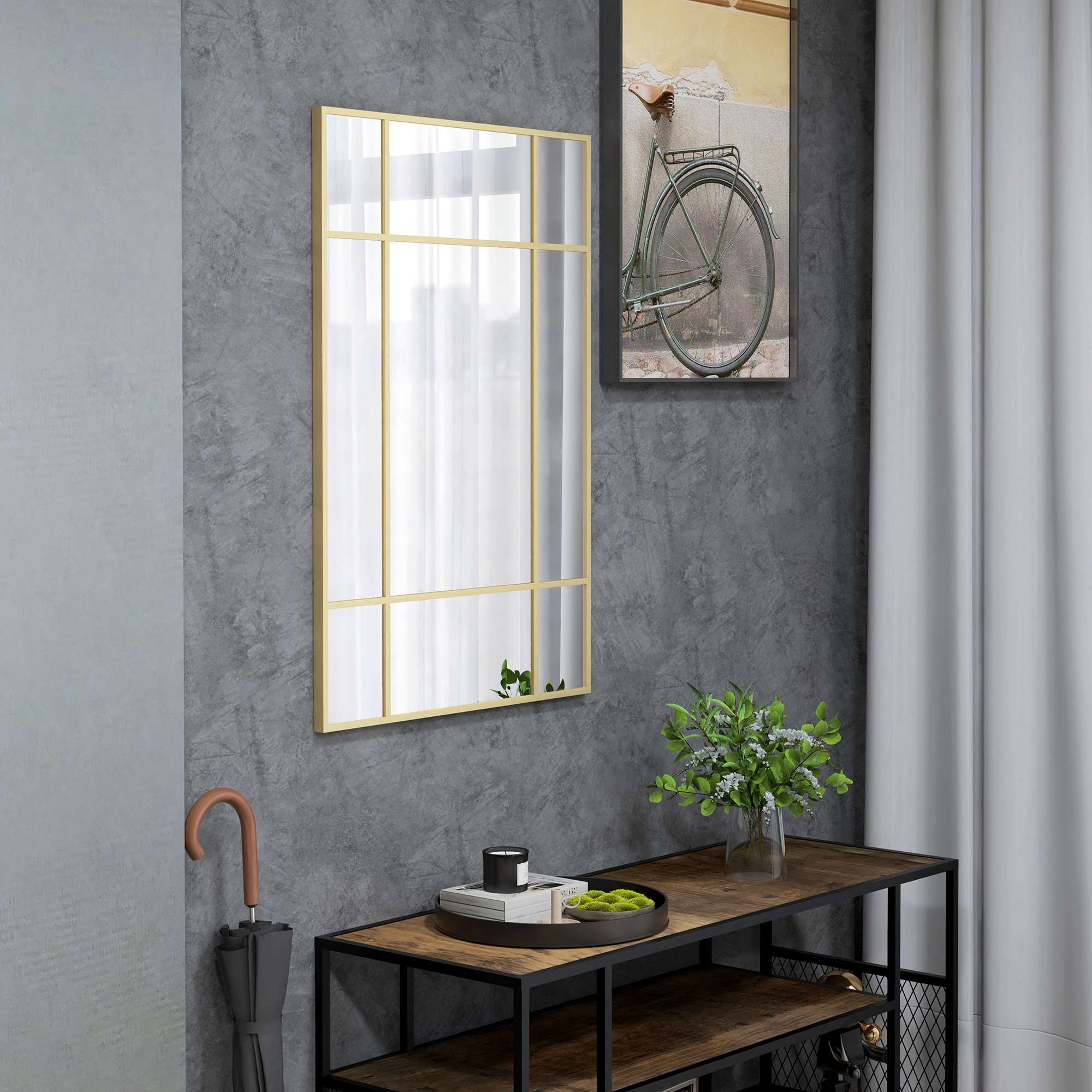 Un espejo dorado refleja la luz. Un cuadro de bicicleta cuelga sobre un estante con decoración.