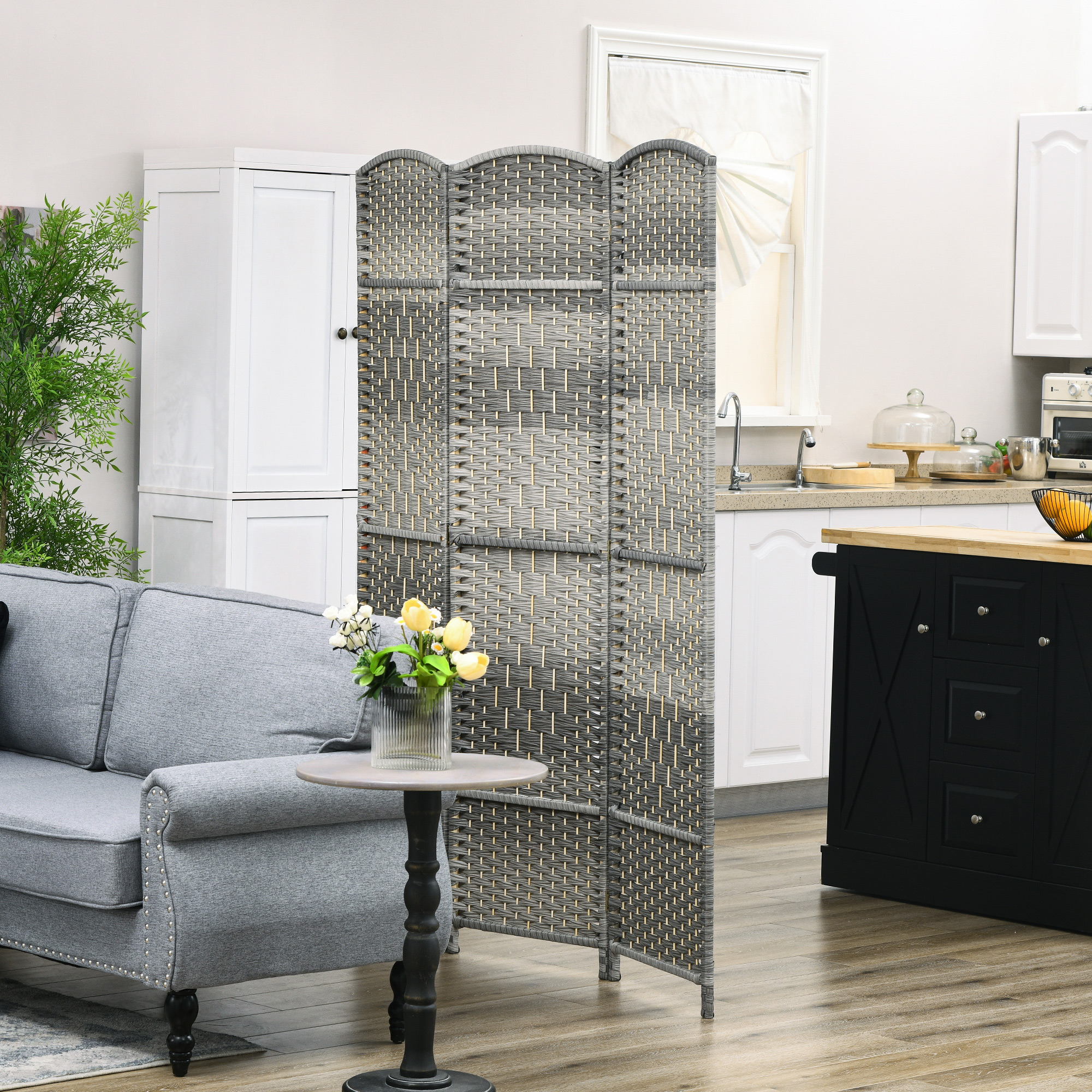 Un sofá gris se sienta junto a un divisor de habitación y una mesa con flores.