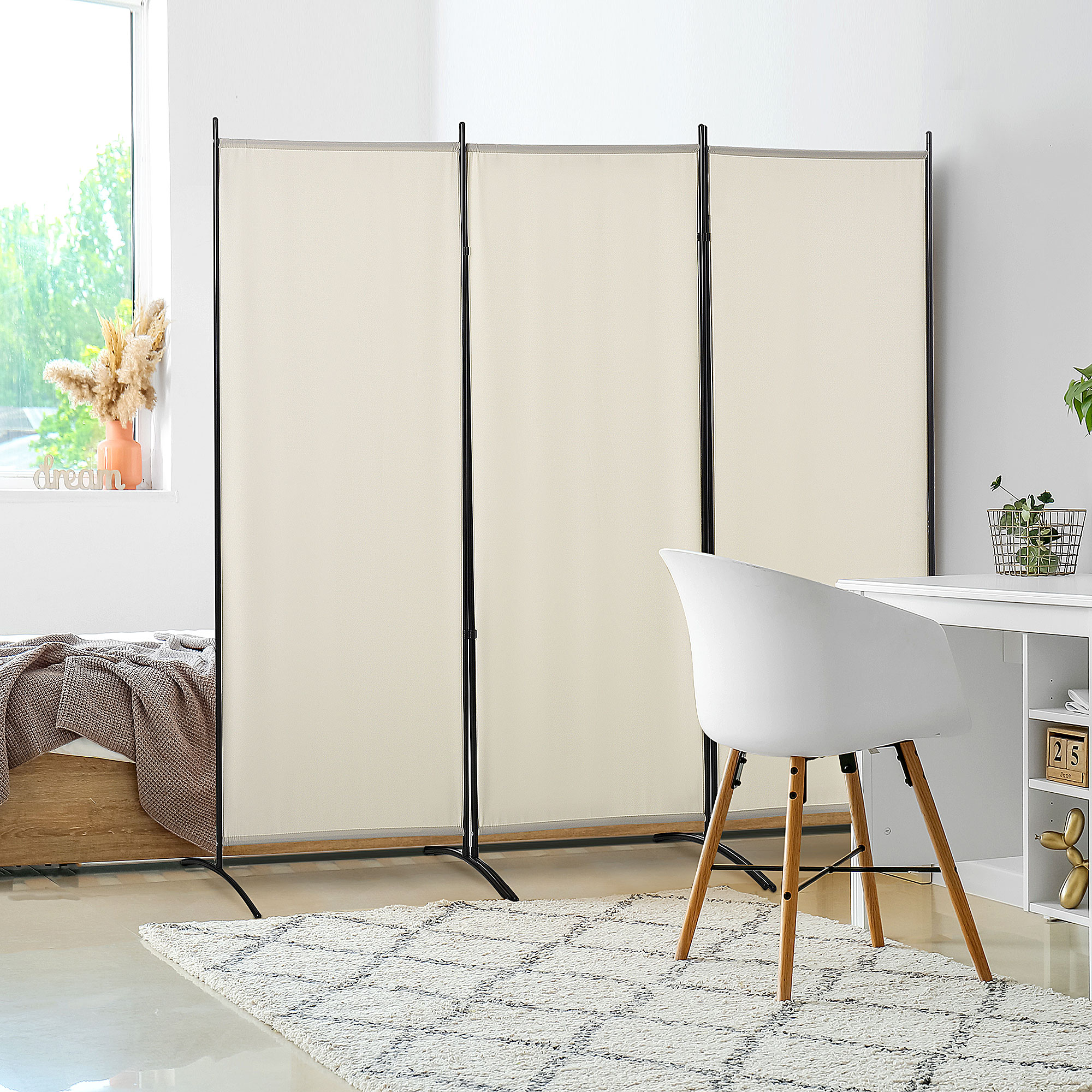 Un separador de ambientes color crema junto a una cama y un escritorio con silla blanca.