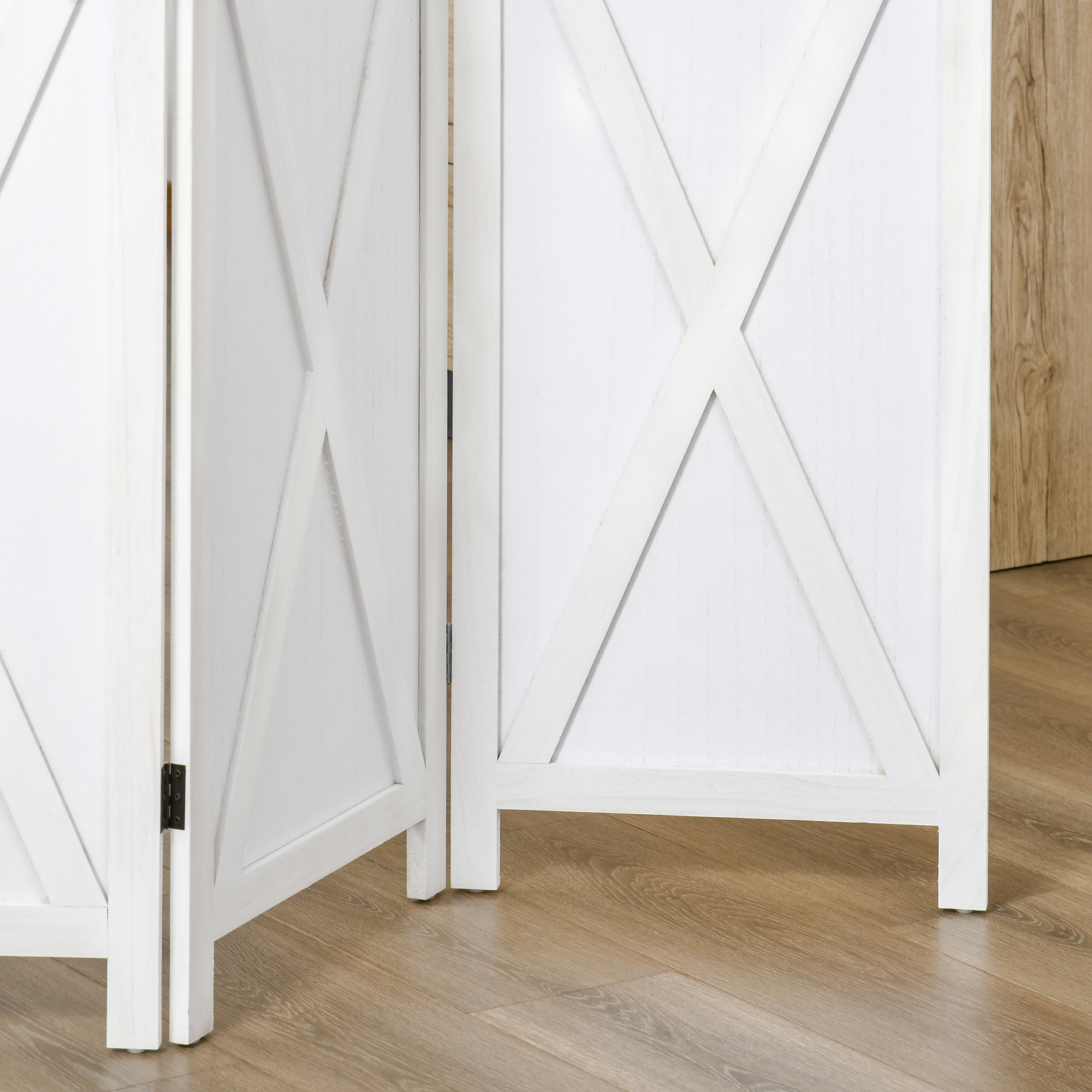 Un separador de ambientes blanco con patrón X sobre suelo de madera.