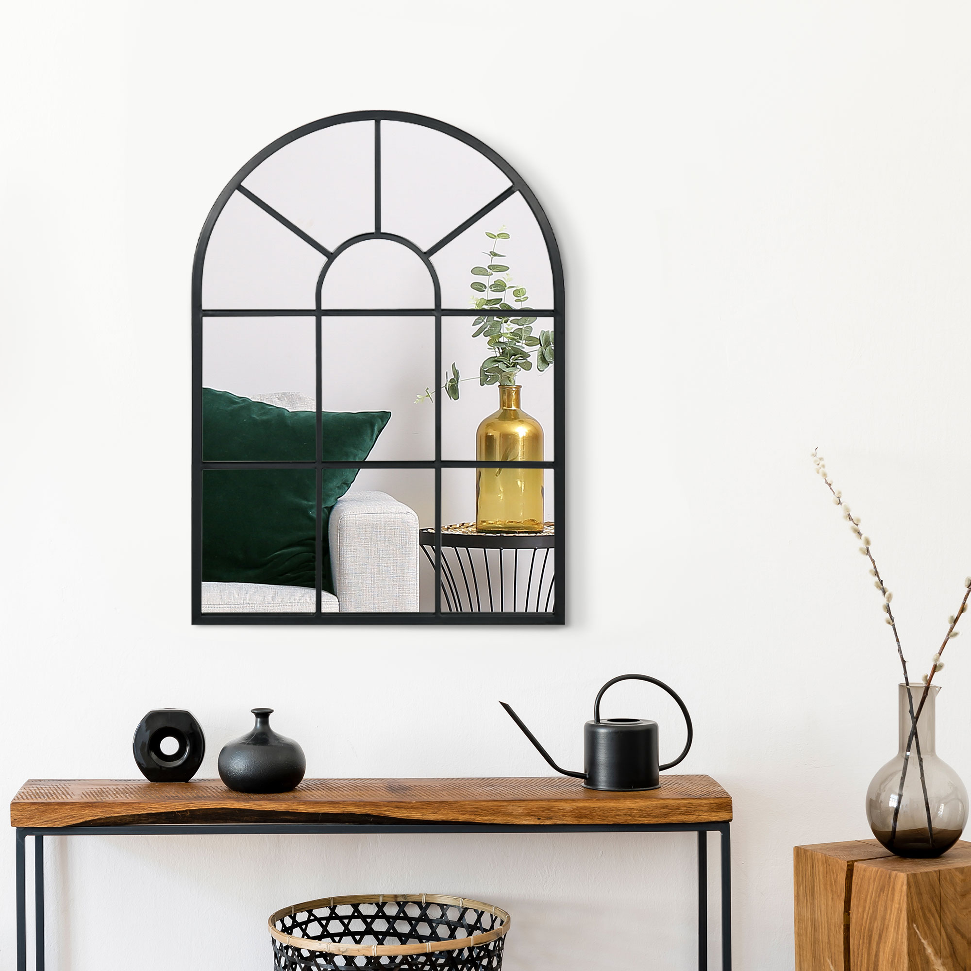 Un espejo con marco de ventana sobre una mesa de madera con decoración.