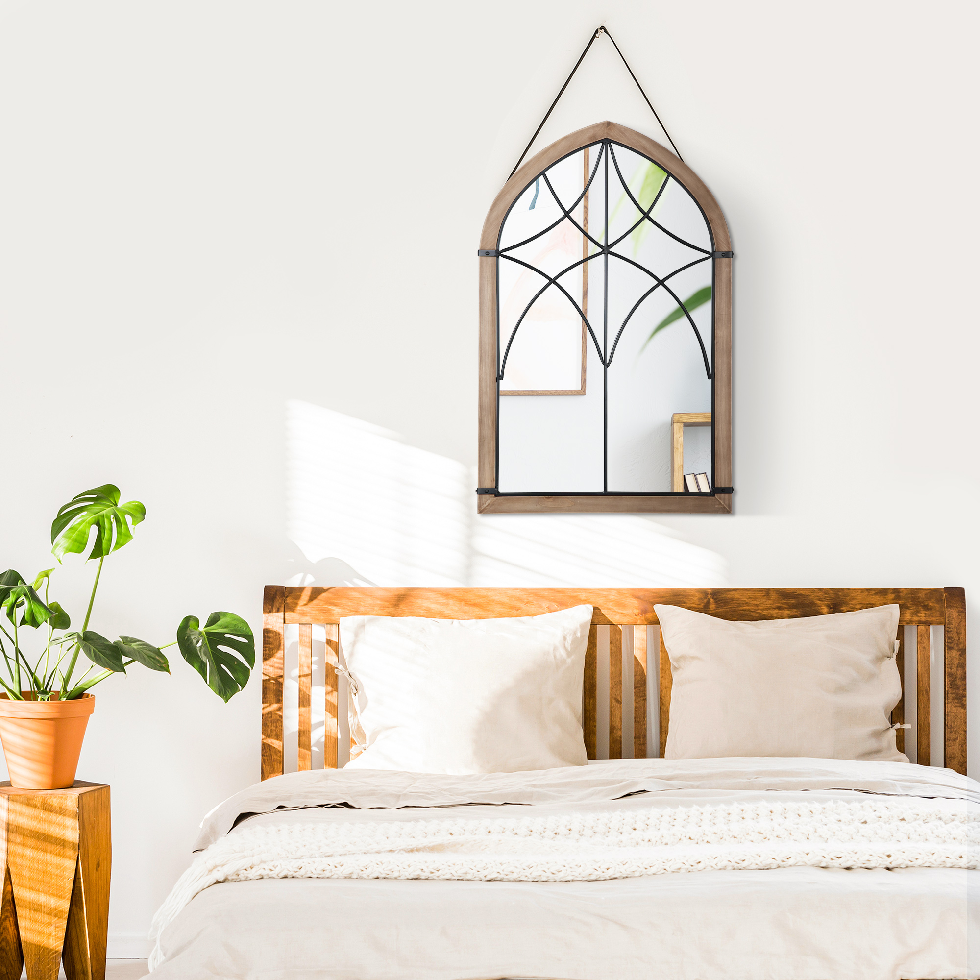 Un dormitorio acogedor con cama de madera, almohadas blancas y planta de monstera.
